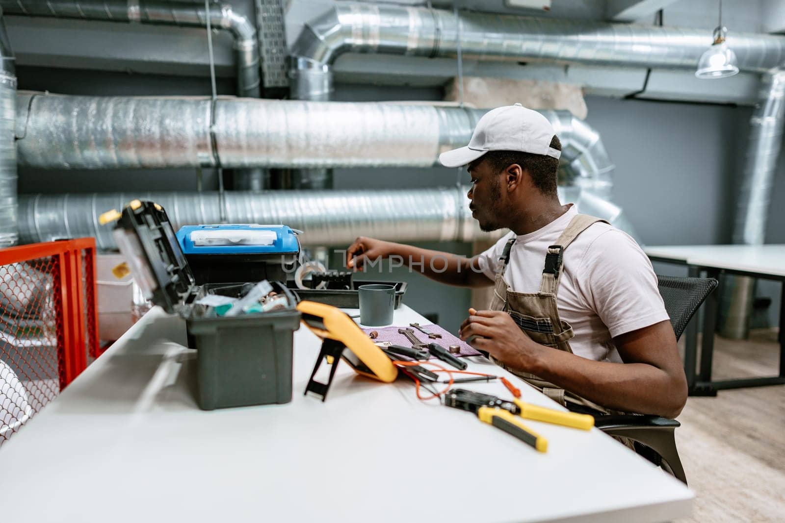 A technician is focused on assembling electrical tools at a well-lit workshop. He utilizes various equipment and tools from an organized work area, ensuring precision in his tasks.