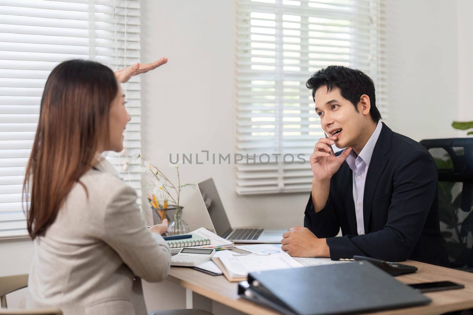 A woman enthusiastically explaining financial concepts to a man, fostering collaboration in a contemporary office setting.