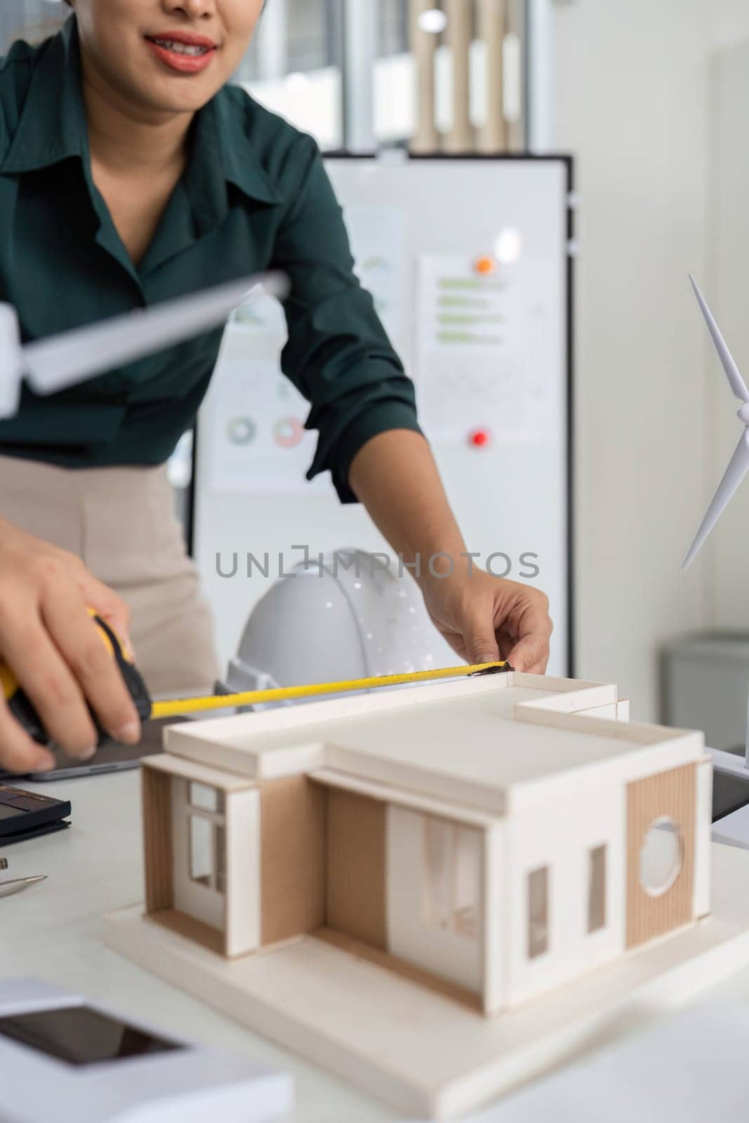 An architect focuses on precision while measuring a building model, ensuring accuracy in the design process for a sustainable project.