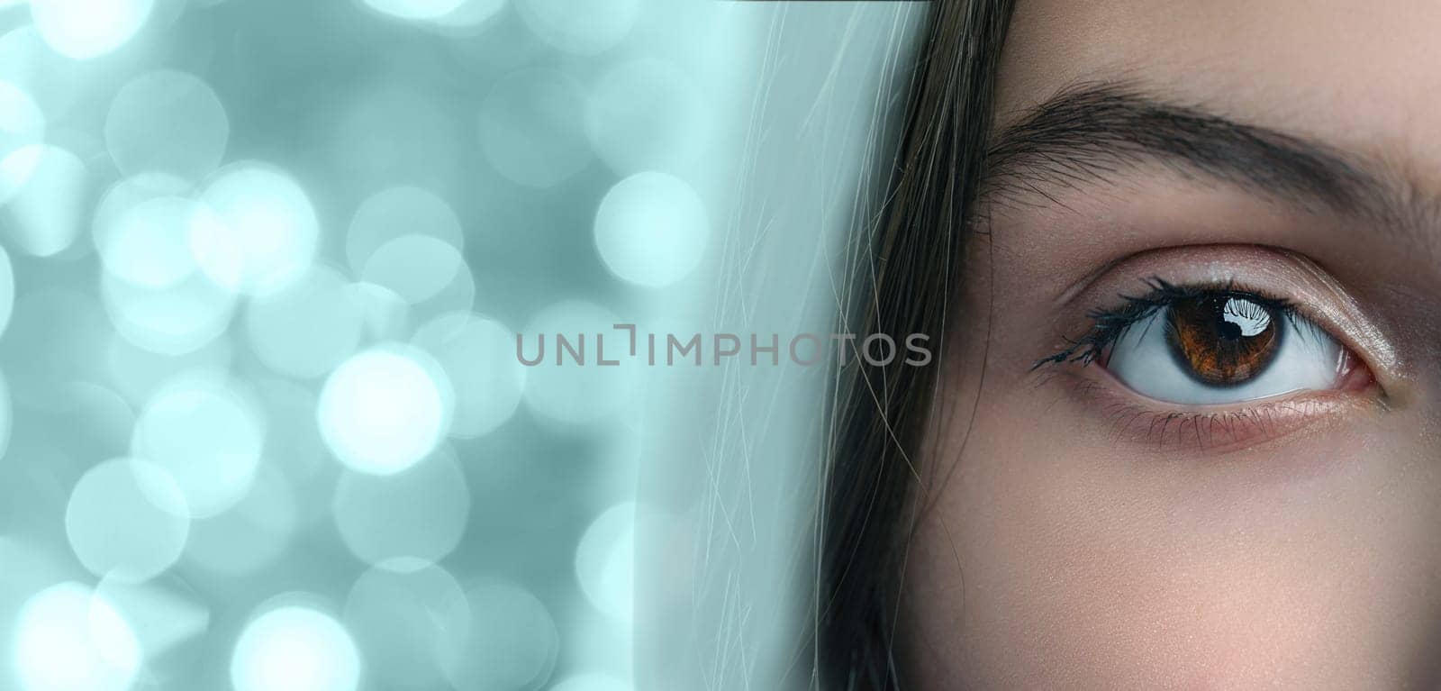 A close-up of a striking eye reveals deep brown hues and a reflective surface. The background features soft, out-of-focus lights that enhance the overall beauty of the gaze.