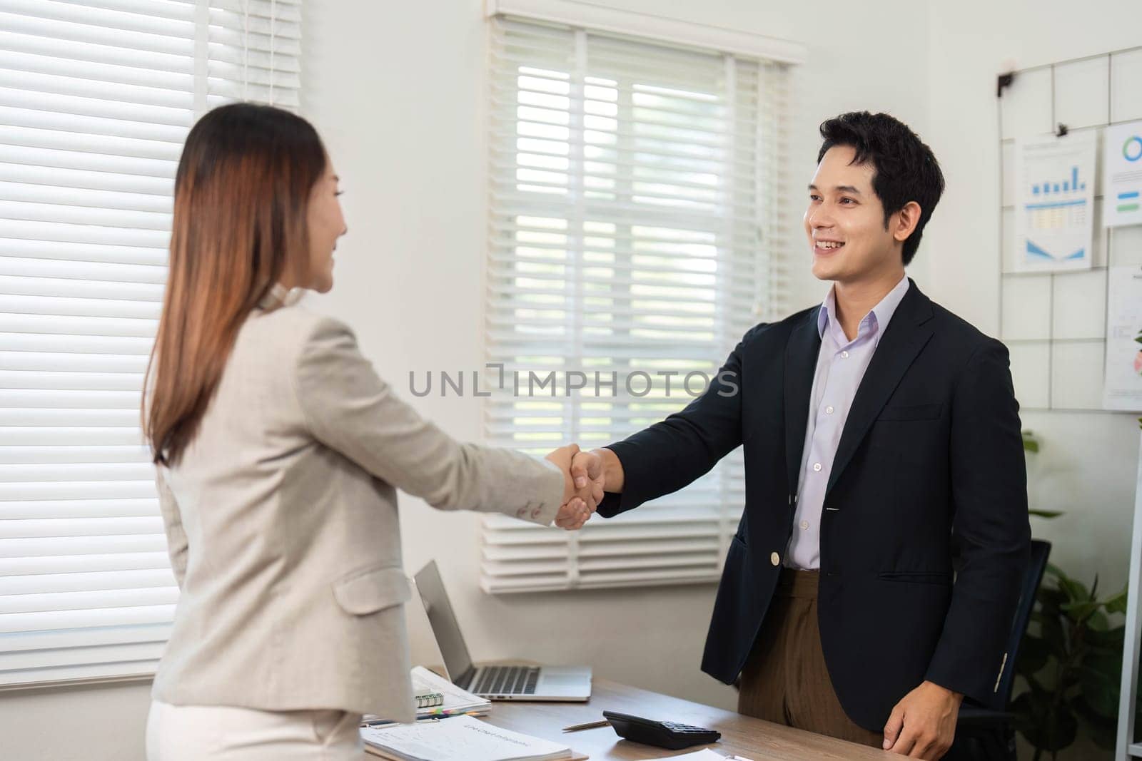 A professional handshake between two colleagues, symbolizing trust and partnership in a modern office environment.