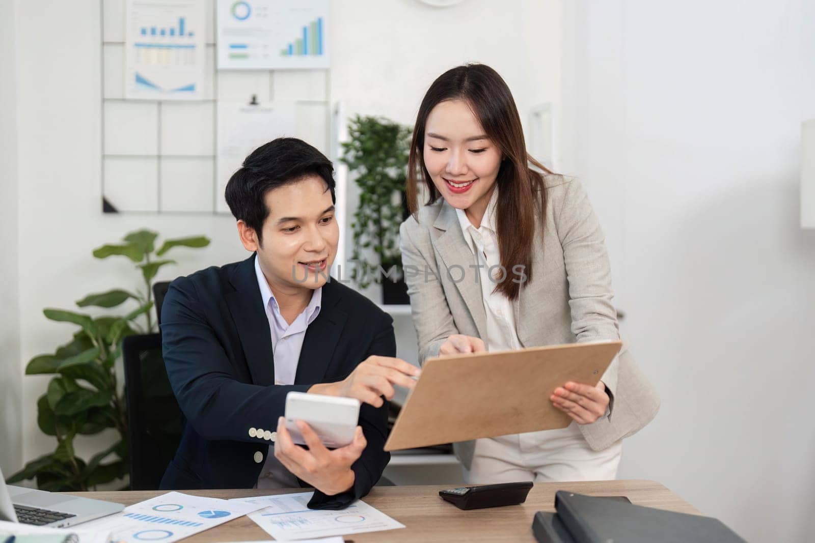 Two business professionals celebrate their success while discussing financial data, showcasing teamwork and motivation in a bright office.
