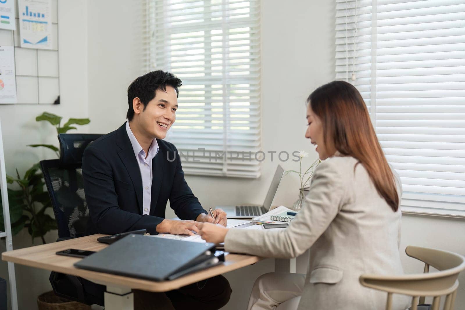 A businessman and businesswoman sharing insights and discussing financial strategies, fostering a positive work environment.