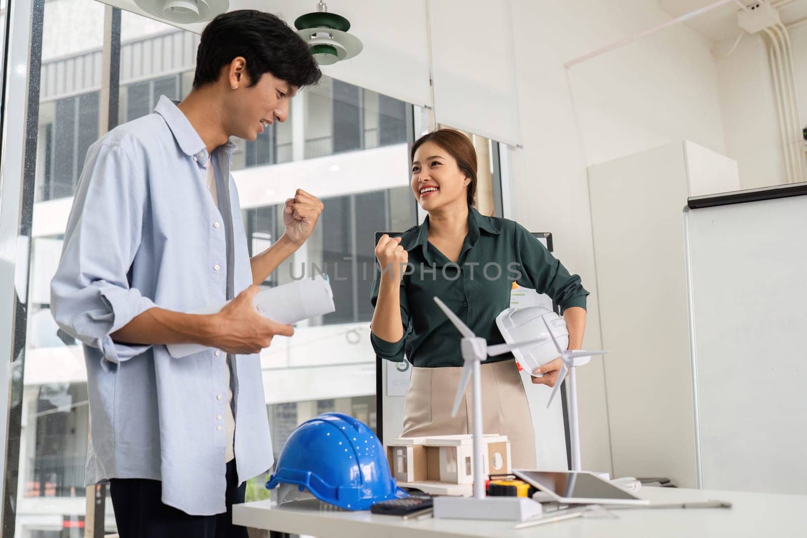 Two engineers express joy and excitement after a successful project discussion in a contemporary workspace.