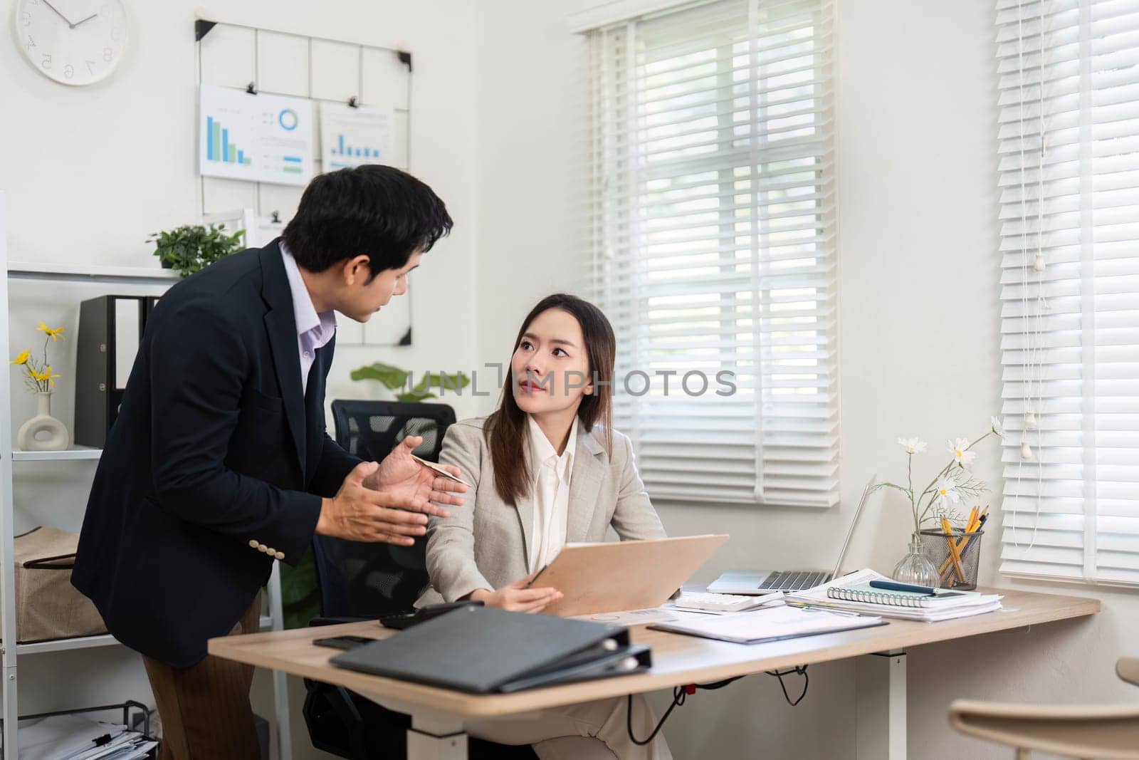 Two professionals discuss financial strategies and planning while reviewing documents in a modern workspace, showcasing teamwork and collaboration.