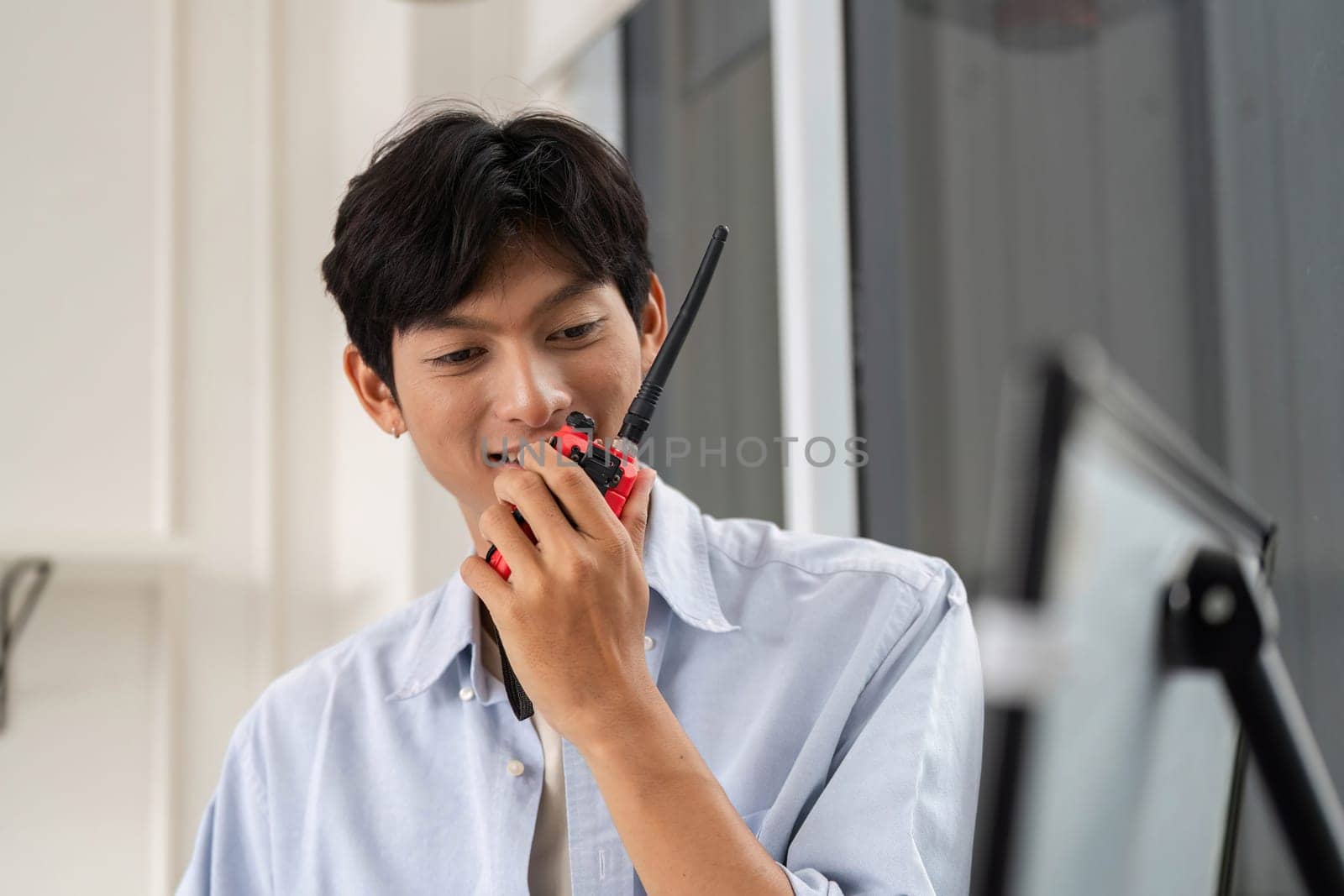 A young engineer communicates via walkie-talkie, ensuring smooth project coordination in a modern construction setting.