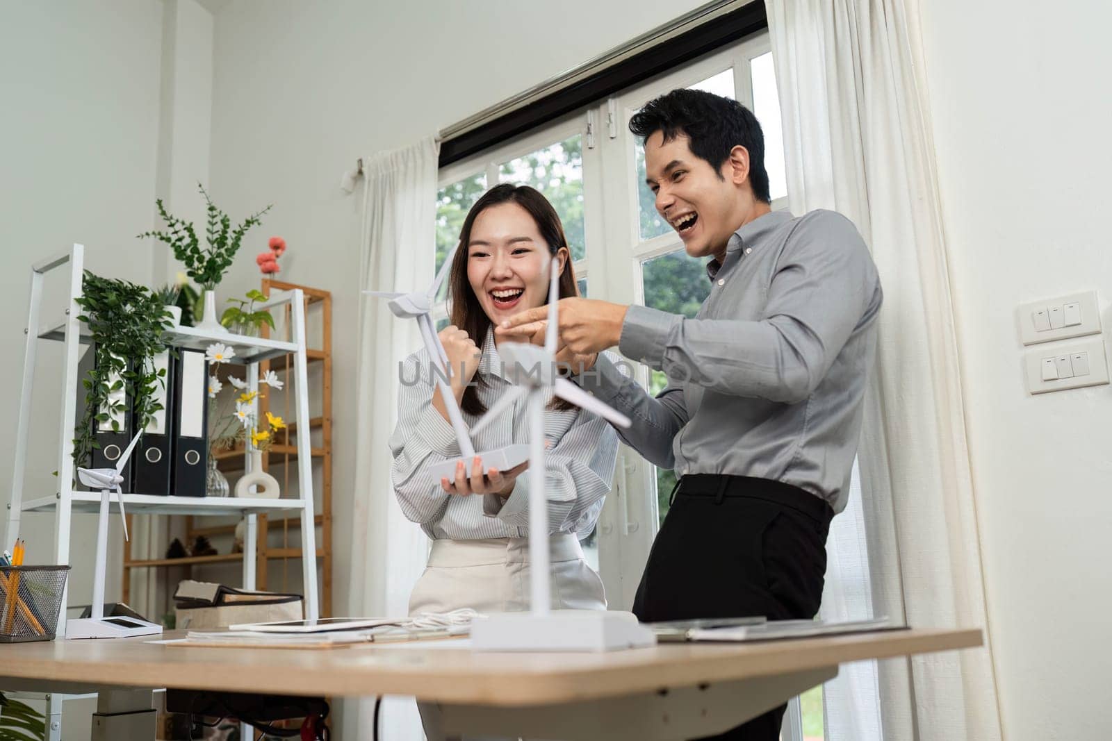 Two business professionals express joy and collaboration in a modern workspace, emphasizing ESG values and teamwork.