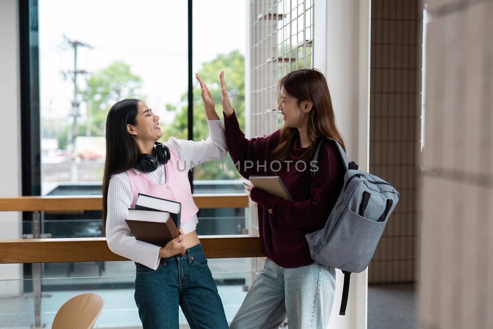 Two students celebrate their collaborative efforts with a high-five, showcasing camaraderie and the joy of achievement in an encouraging school setting.