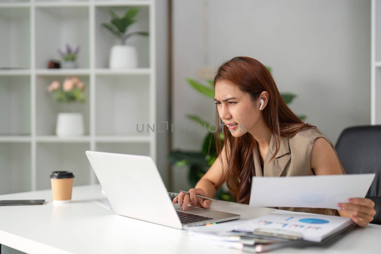 A young woman furrows her brow as she reviews her laptop screen, tackling challenges in her work environment while seeking solutions with determination.