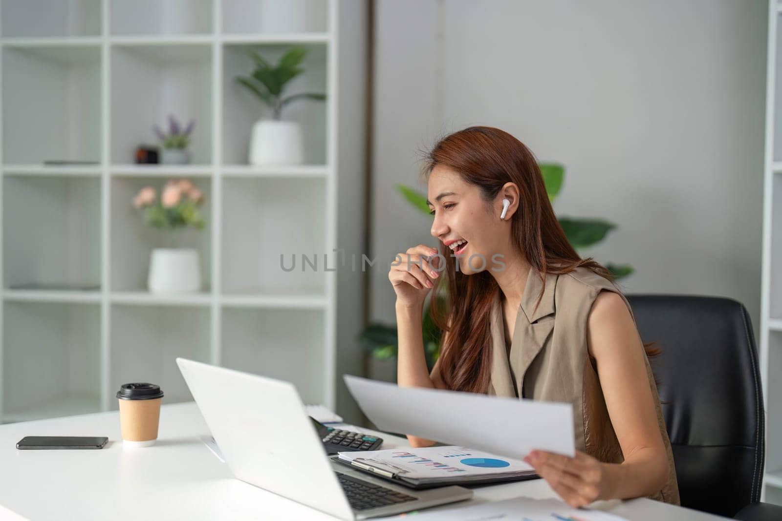 A young woman enjoys her work as she reacts joyfully to her screen, reflecting the positive aspects of teamwork in a digital environment.