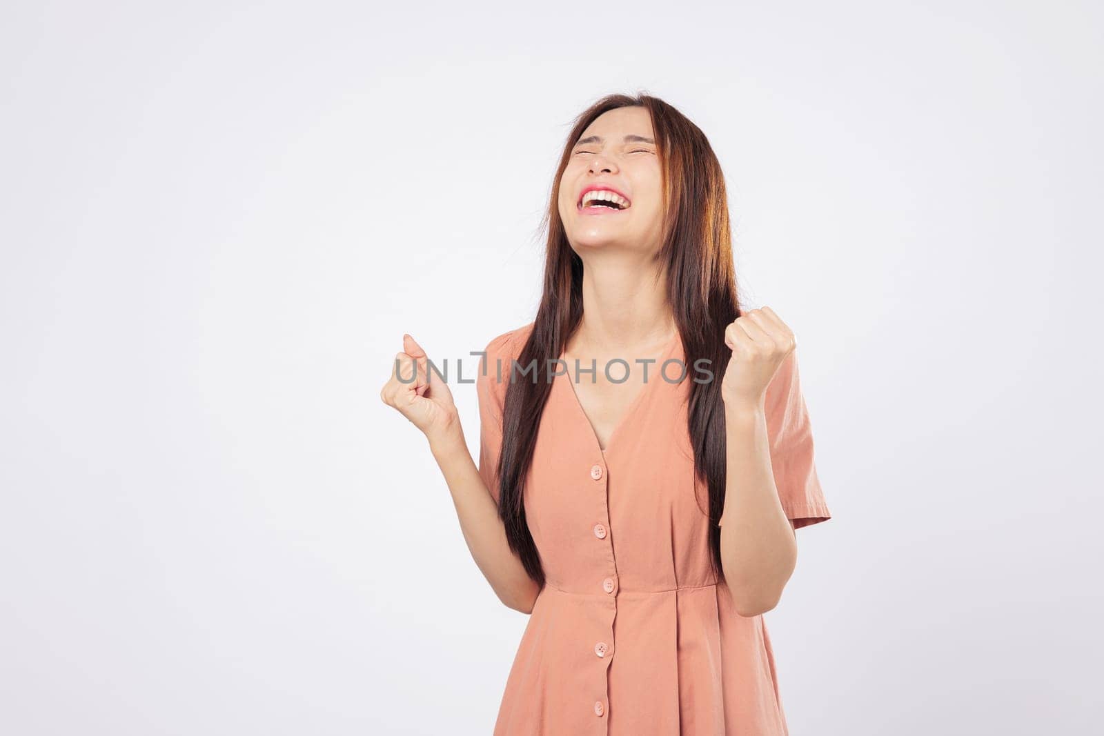 Excited businesswoman excited and overjoyed by success expresses victory with raised fists smiling brightly isolated studio white background symbolizing strength confidence and pride