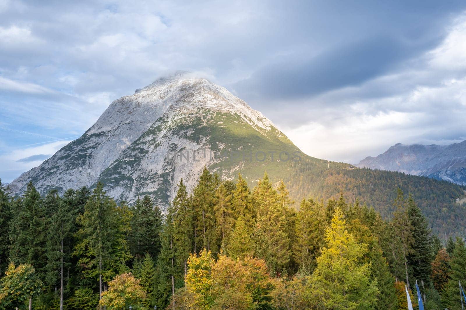 The breathtaking mountain landscape showcases vibrant trees and features dramatic skies that captivate the senses