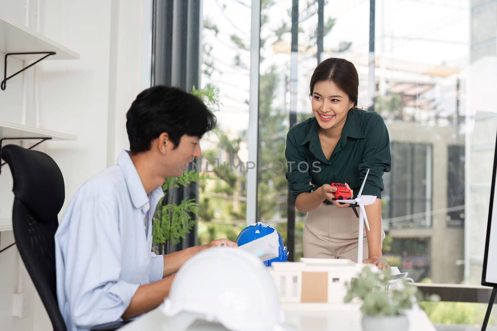 A smiling woman shares ideas with her colleague, emphasizing teamwork and innovation in sustainable architecture.