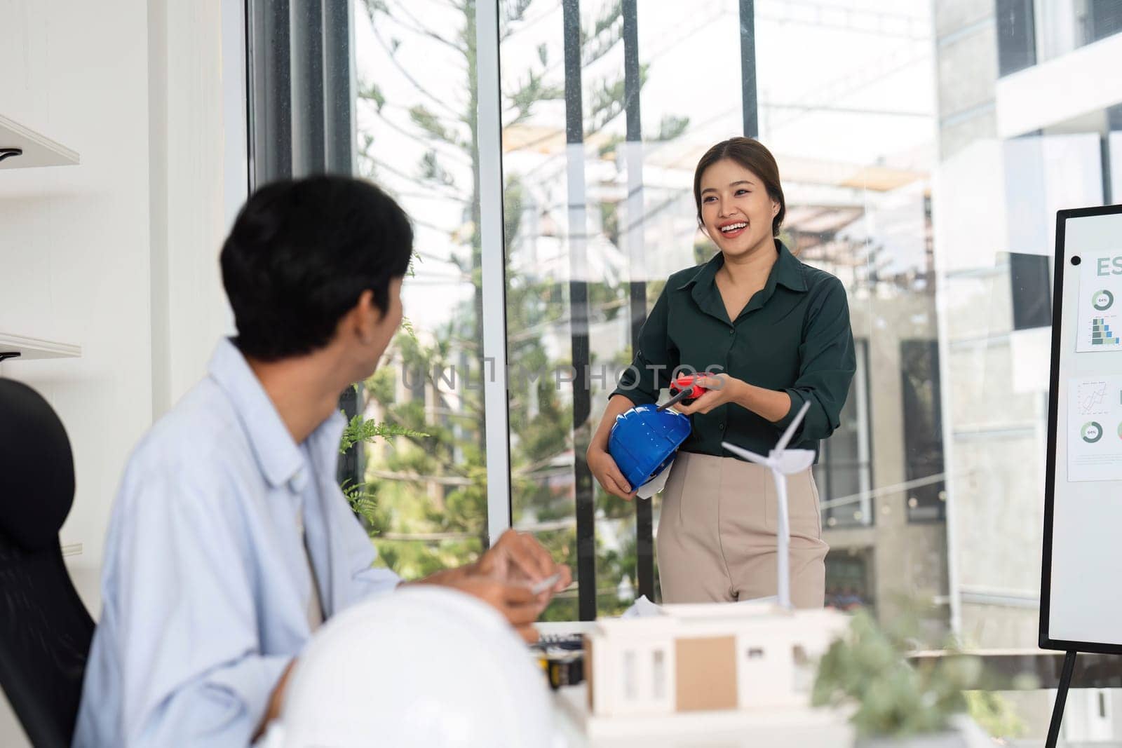 A young woman presents ideas while a man takes notes, highlighting teamwork and innovation in sustainable design.