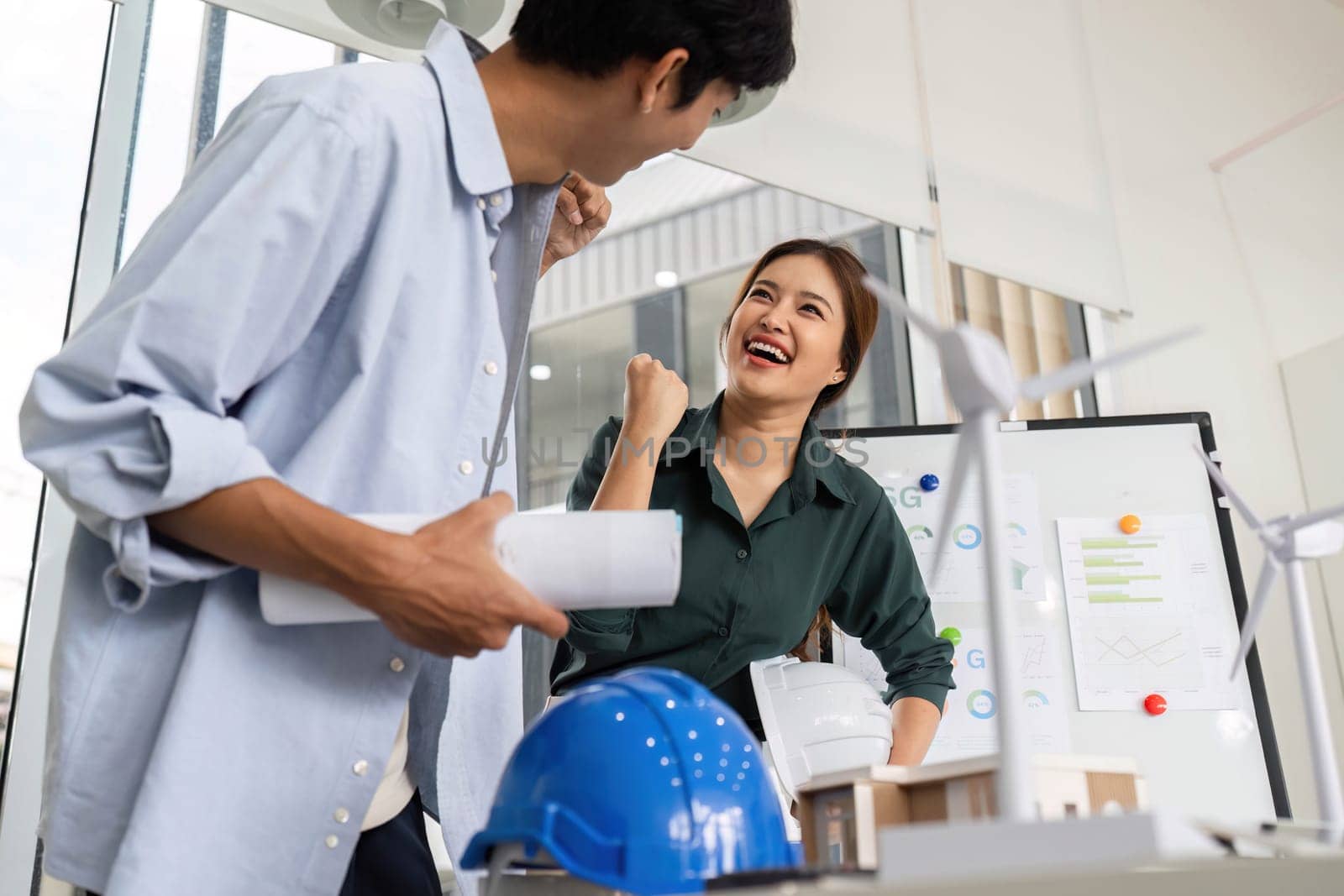 Engineers express excitement and joy while discussing their successful project in a modern office environment.