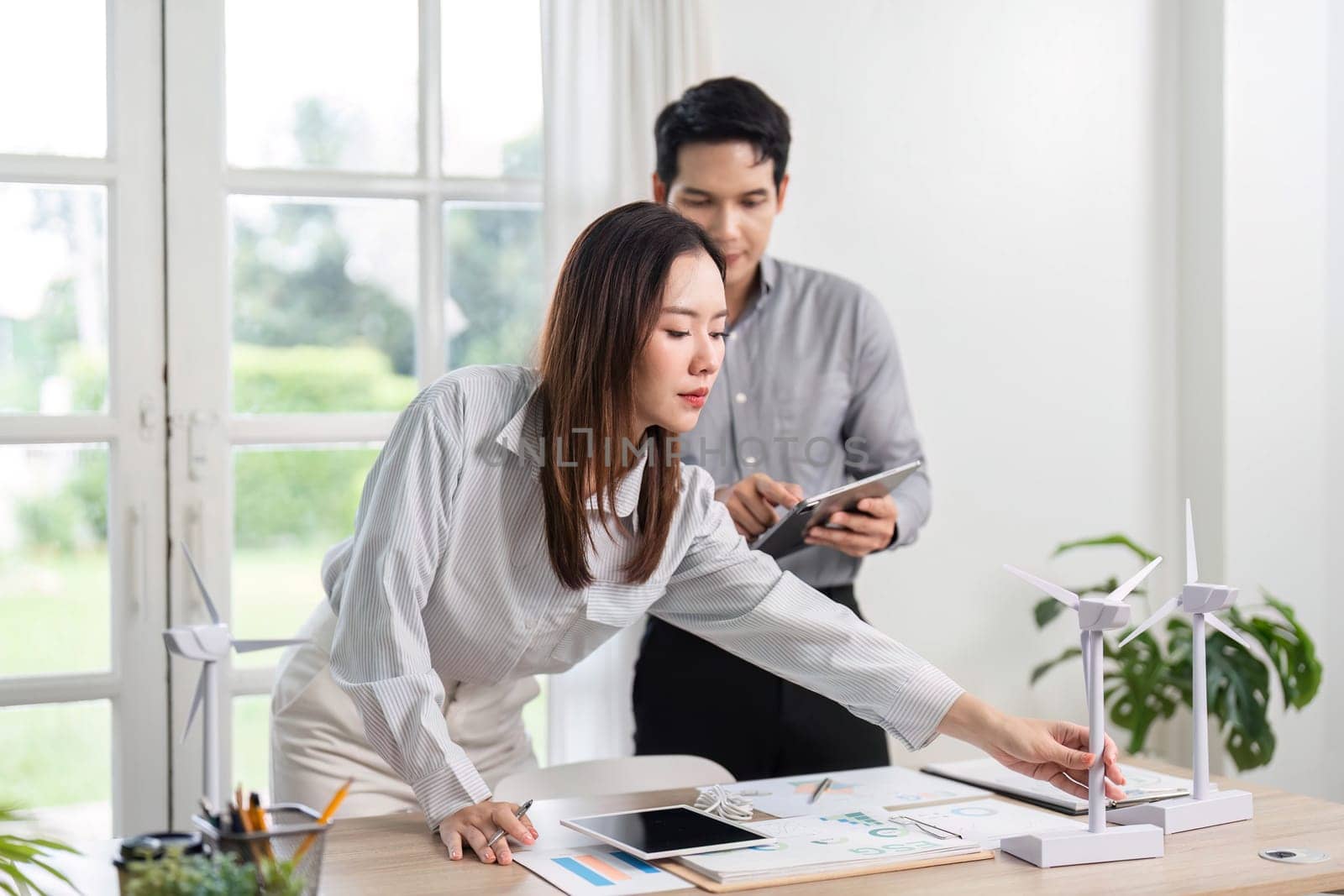 Business professionals actively engage in analyzing renewable energy concepts and ESG initiatives in a collaborative office environment.