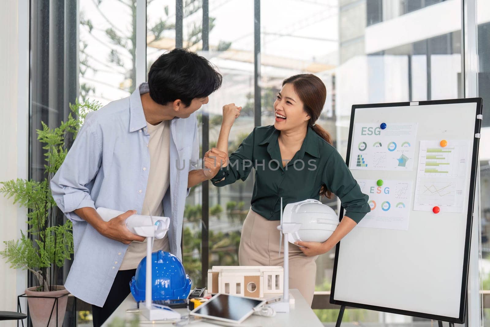 Two young engineers celebrate their project's success in a contemporary office, showcasing teamwork and enthusiasm for innovation.