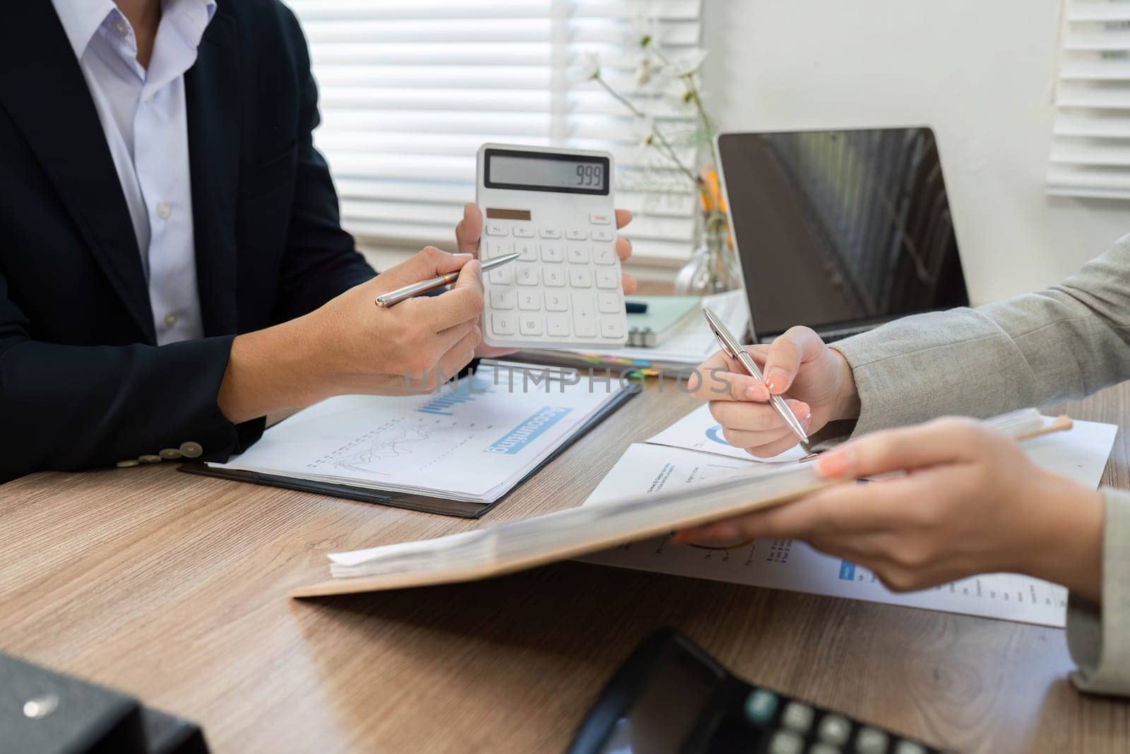 Two business professionals engage in a financial consultation, analyzing data and using a calculator to assess financial strategies.