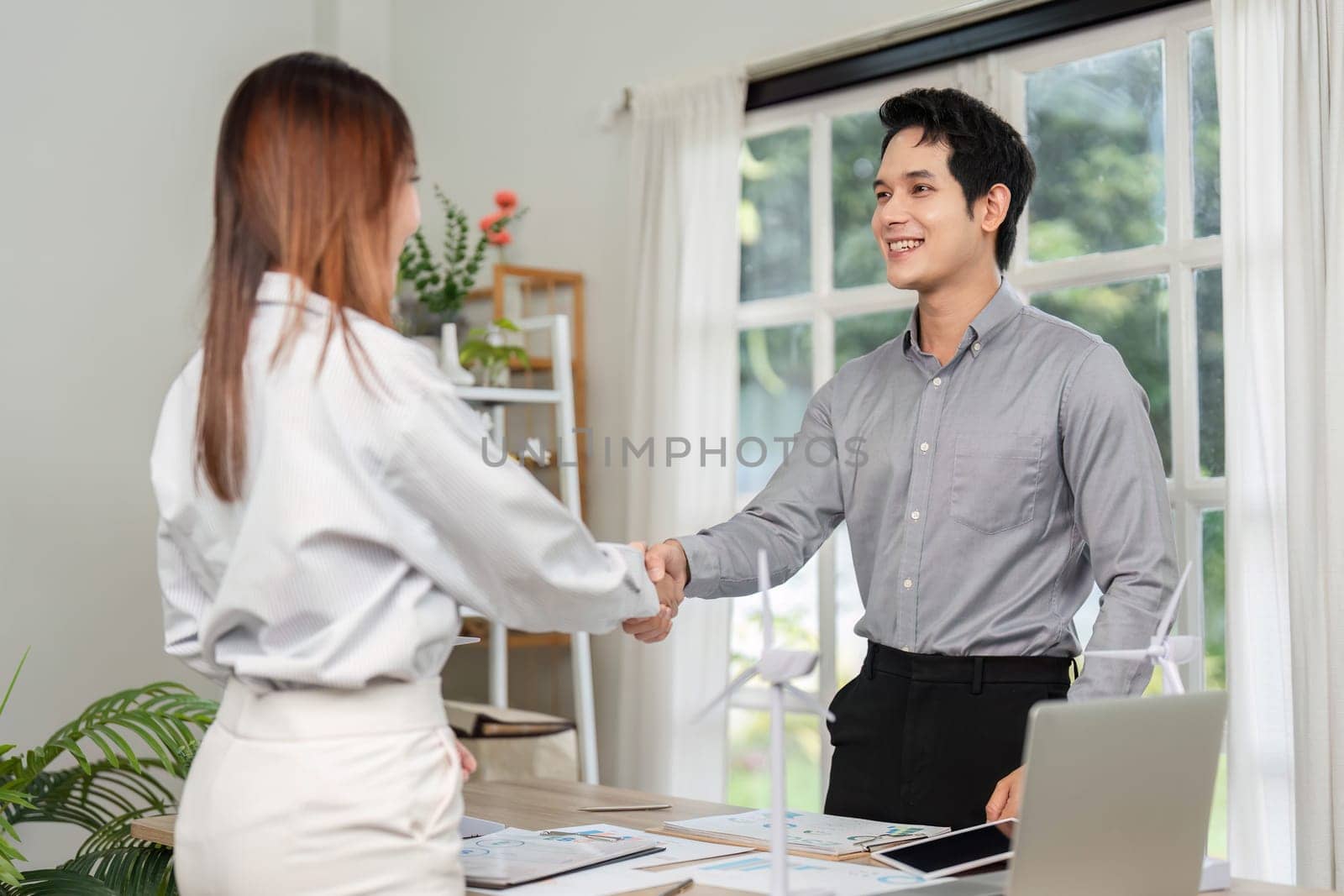 Two business professionals shake hands, finalizing an agreement on an ESG project focused on sustainability and innovation.