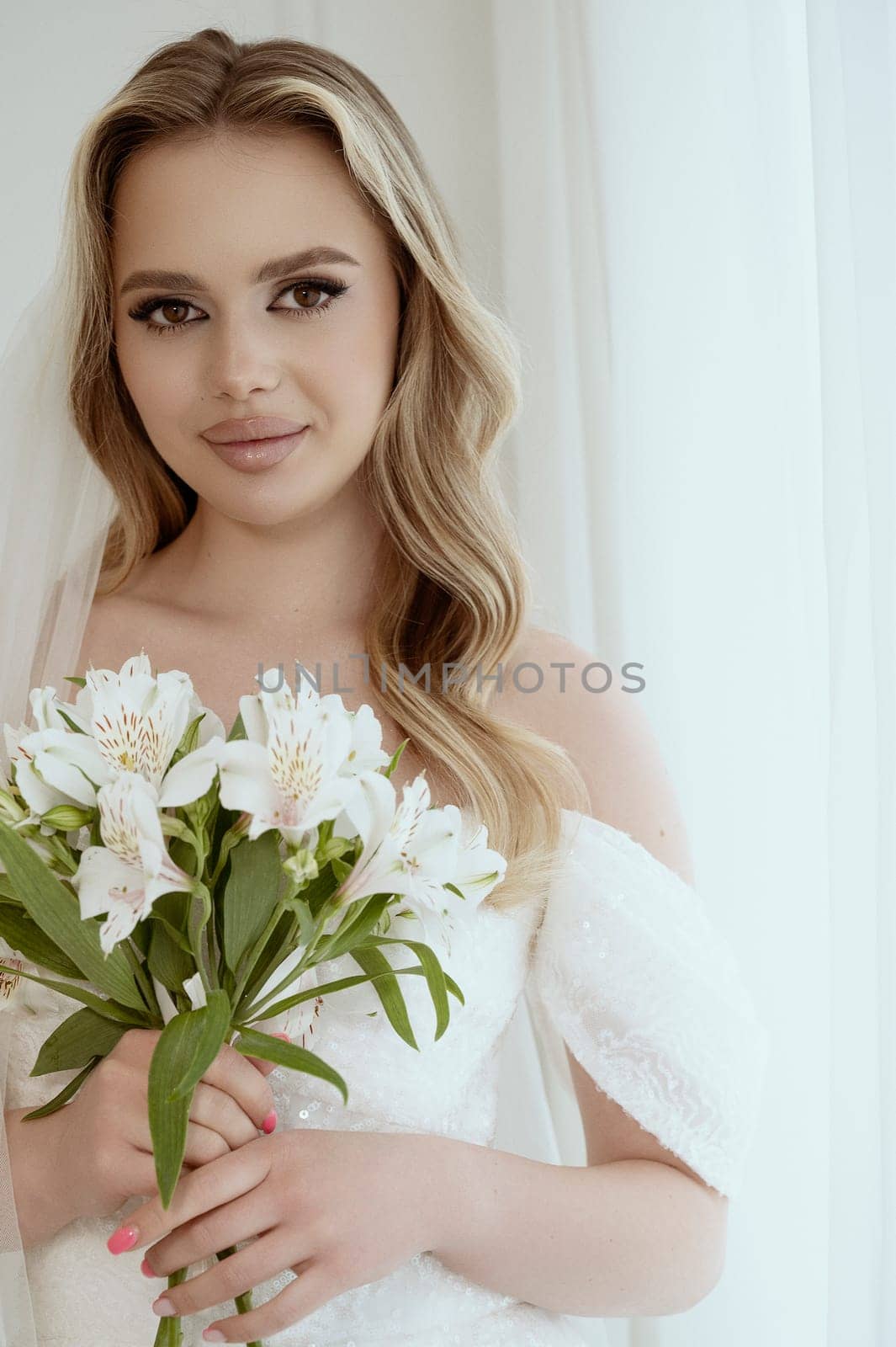 The bride is holding a bouquet in her hands. Elegant white wedding bouquet. Bride holding a bouquet of calla lilies. High quality photo