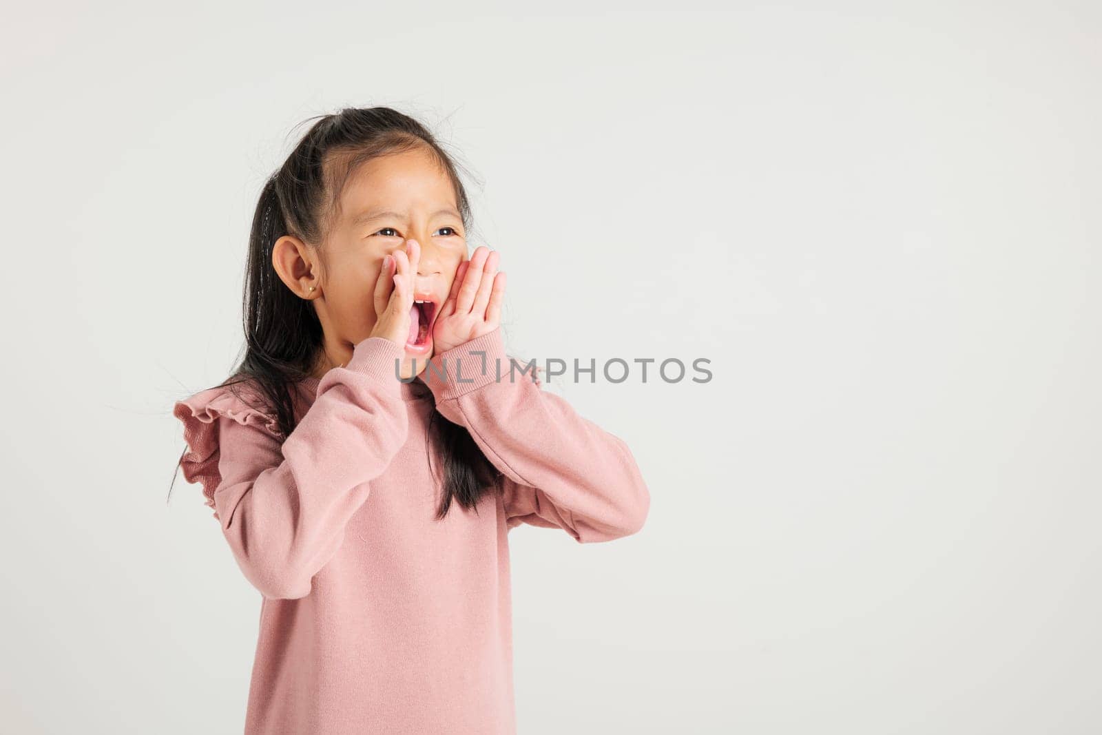 Asian happy portrait cute young kid girl standing hand on mouth talking news announcement studio shot isolated on white background, Thai kindergarten child announcement