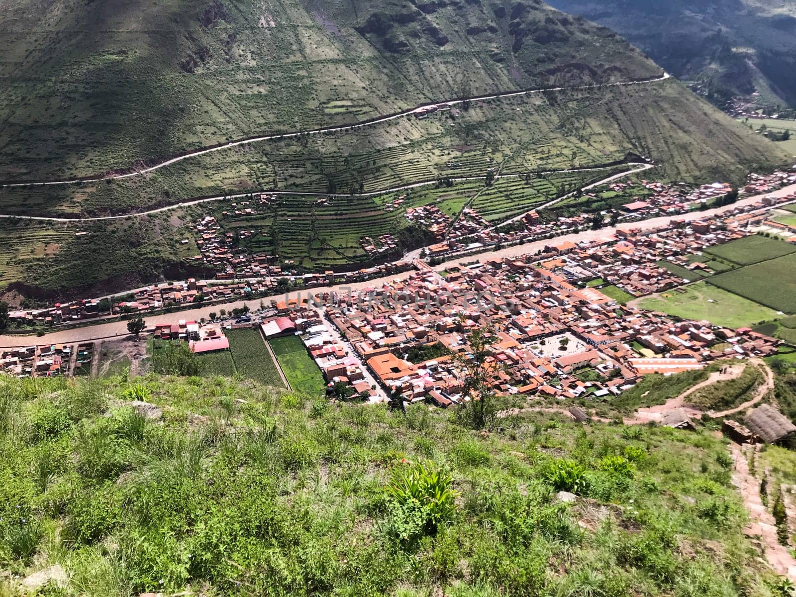 Lush green valley and winding road leading to the town of calca, offering a picturesque view of the peruvian landscape