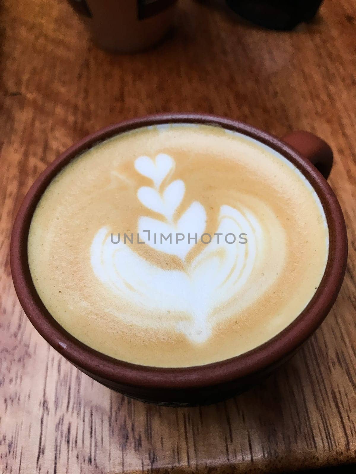 Latte art coffee being served in a cozy cafe in cusco, peru, featuring a delicate leaf design