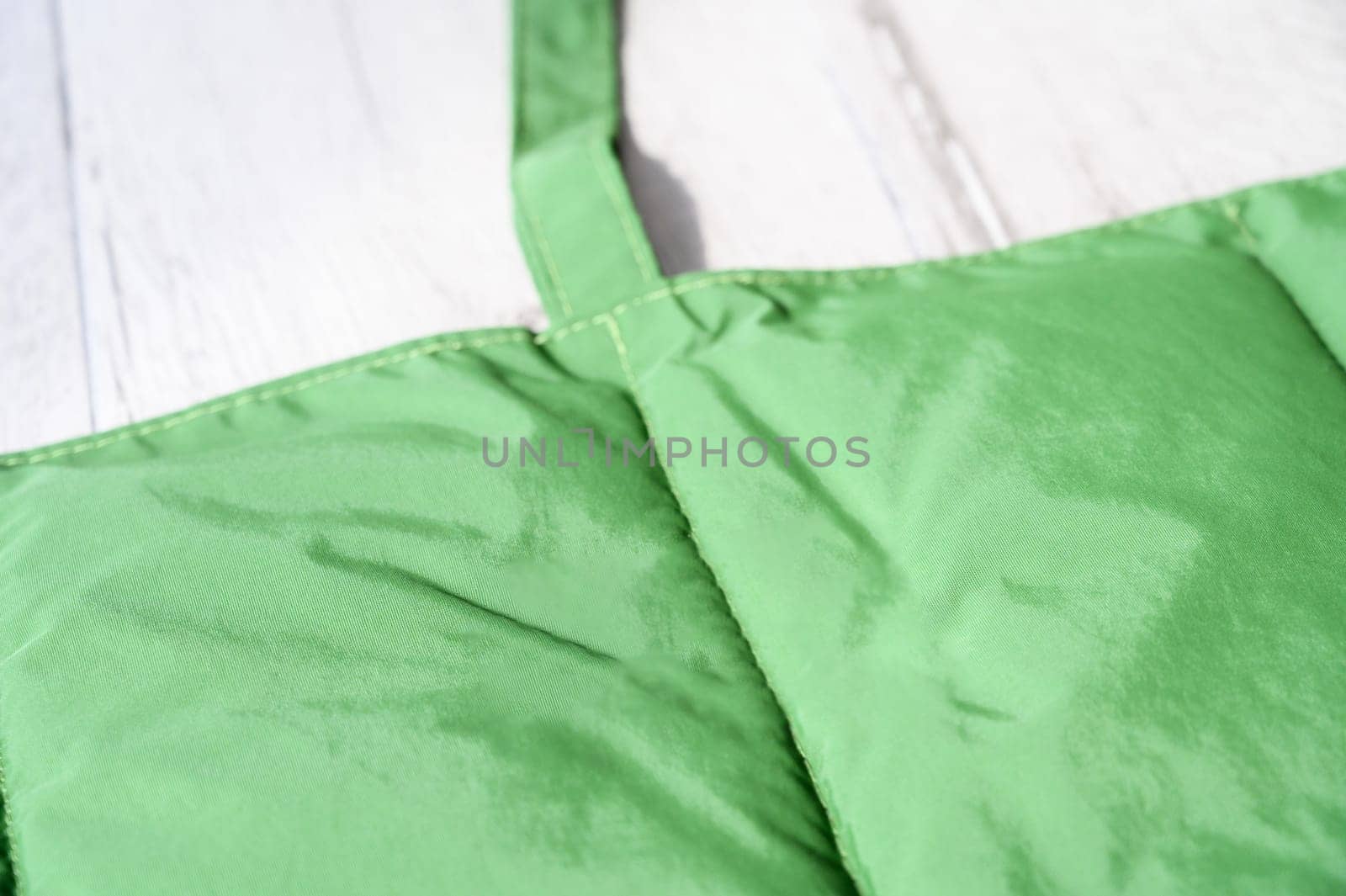 Close up of a green padded mat, designed for pets, placed on a white wooden table, emphasizing its softness and comfort