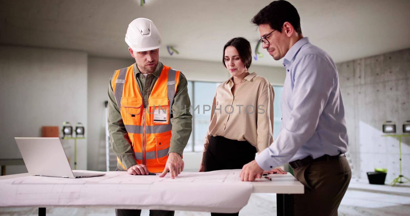Engineer And Architect Inspecting Blueprint With Young Couple In Home.
