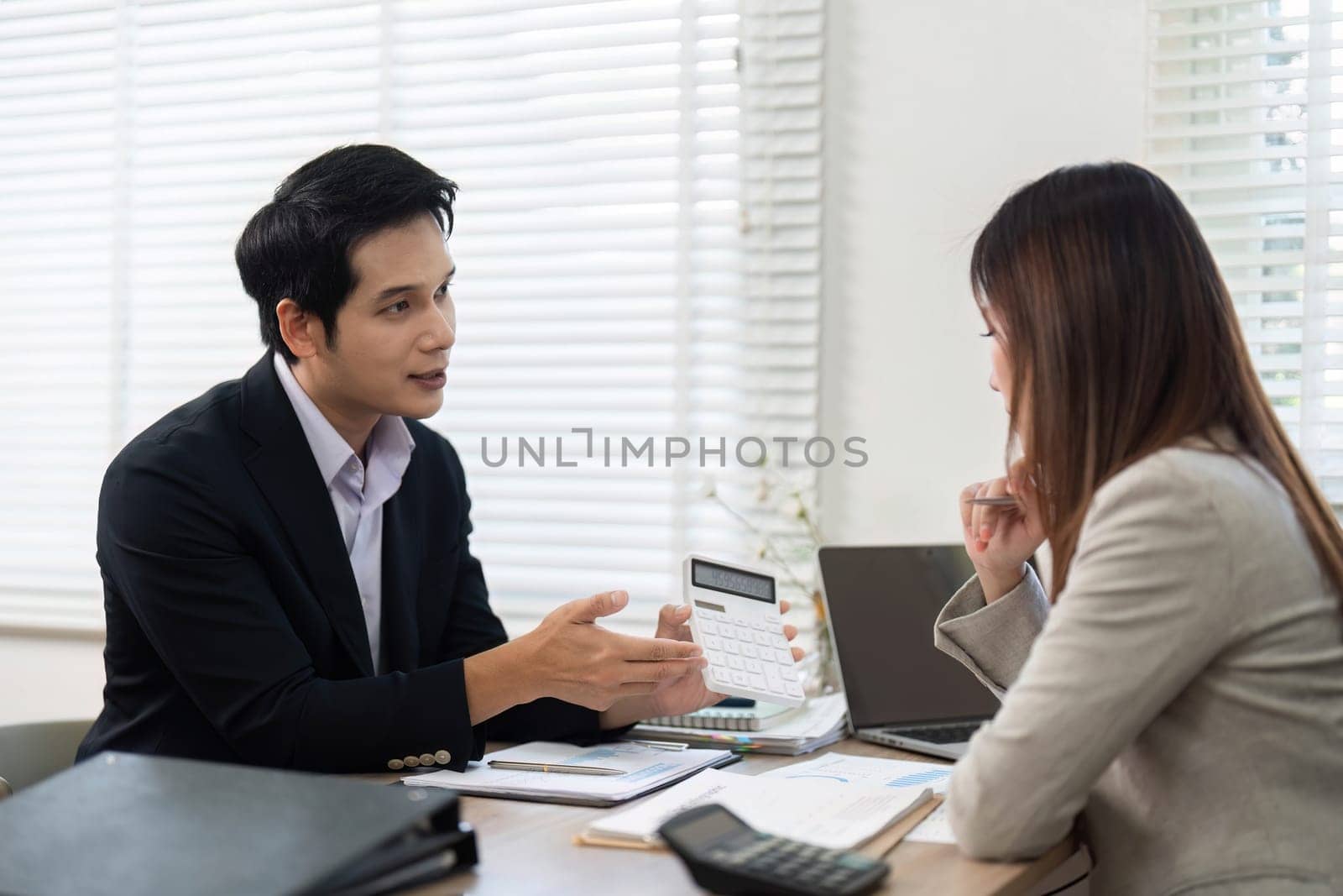 A financial advisor presents data to a client in a modern office, discussing strategies for investment and financial empowerment.