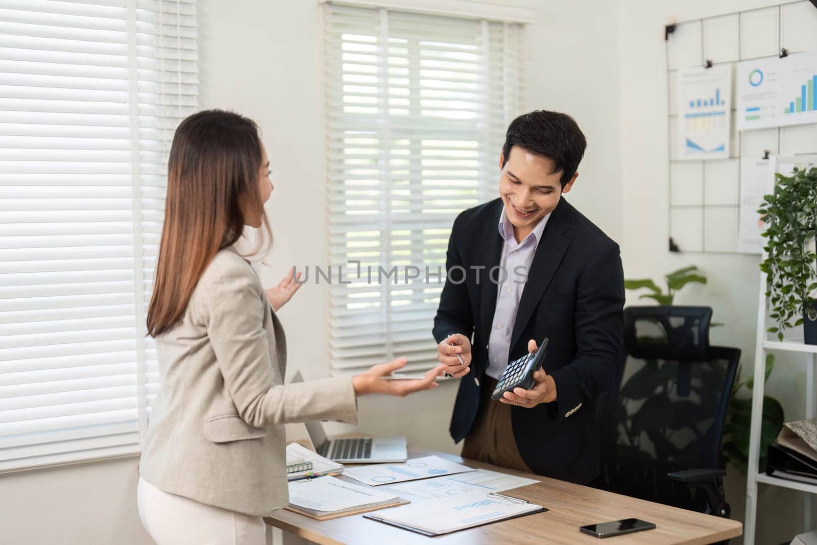 A woman gestures while discussing with a man, showcasing effective communication and teamwork in a bright, contemporary workspace.