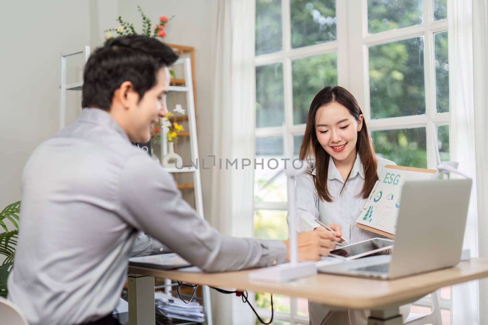 A professional woman presents ESG data to a client, focusing on sustainable practices and corporate governance.