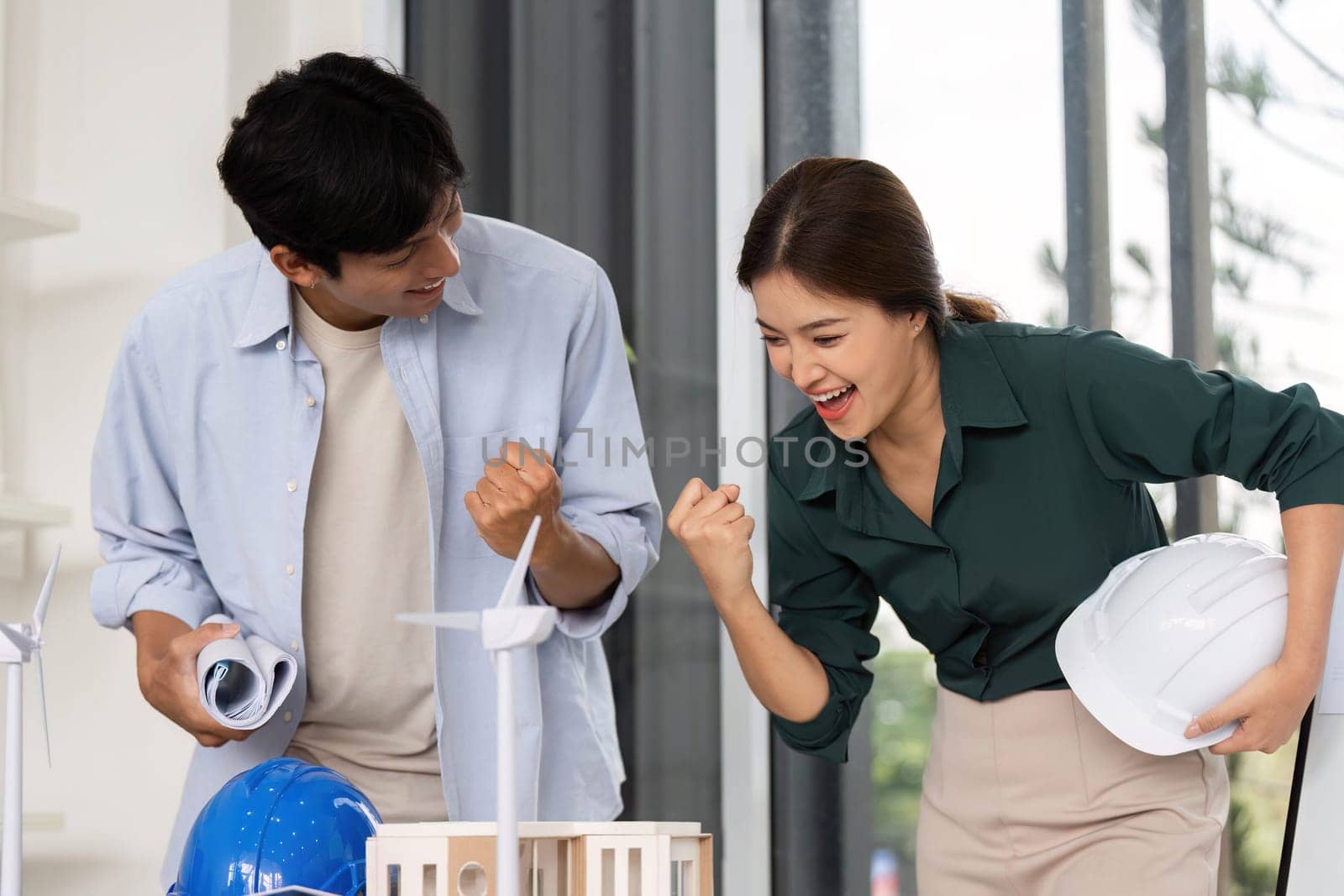A joyful moment between two architects as they celebrate their project's success in a contemporary workspace, showcasing teamwork and innovation.