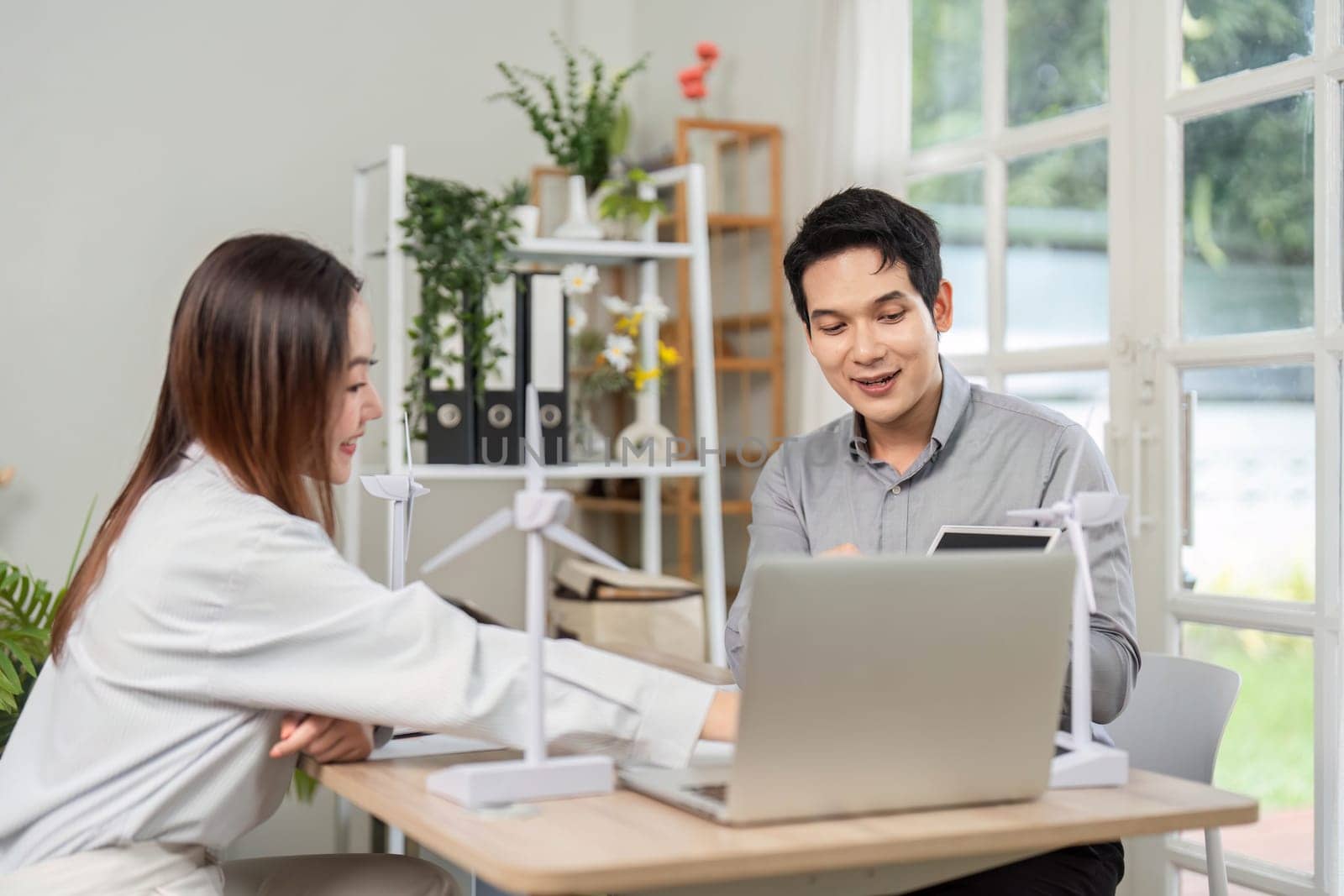 Two business professionals engaged in a discussion about ESG initiatives, focusing on renewable energy solutions in a modern office setting.