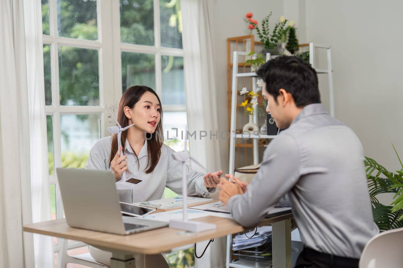 A businesswoman discusses renewable energy strategies with her colleague, emphasizing ESG initiatives in a modern office environment.