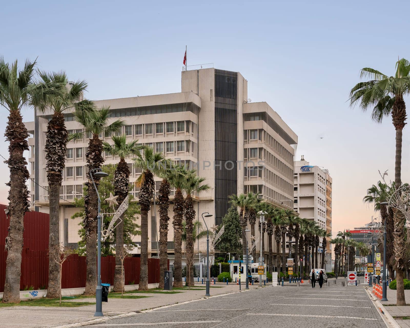 Izmir, Turkey - April 1, 2025: Palm trees line the Kordon promenade, with buildings and people on the street