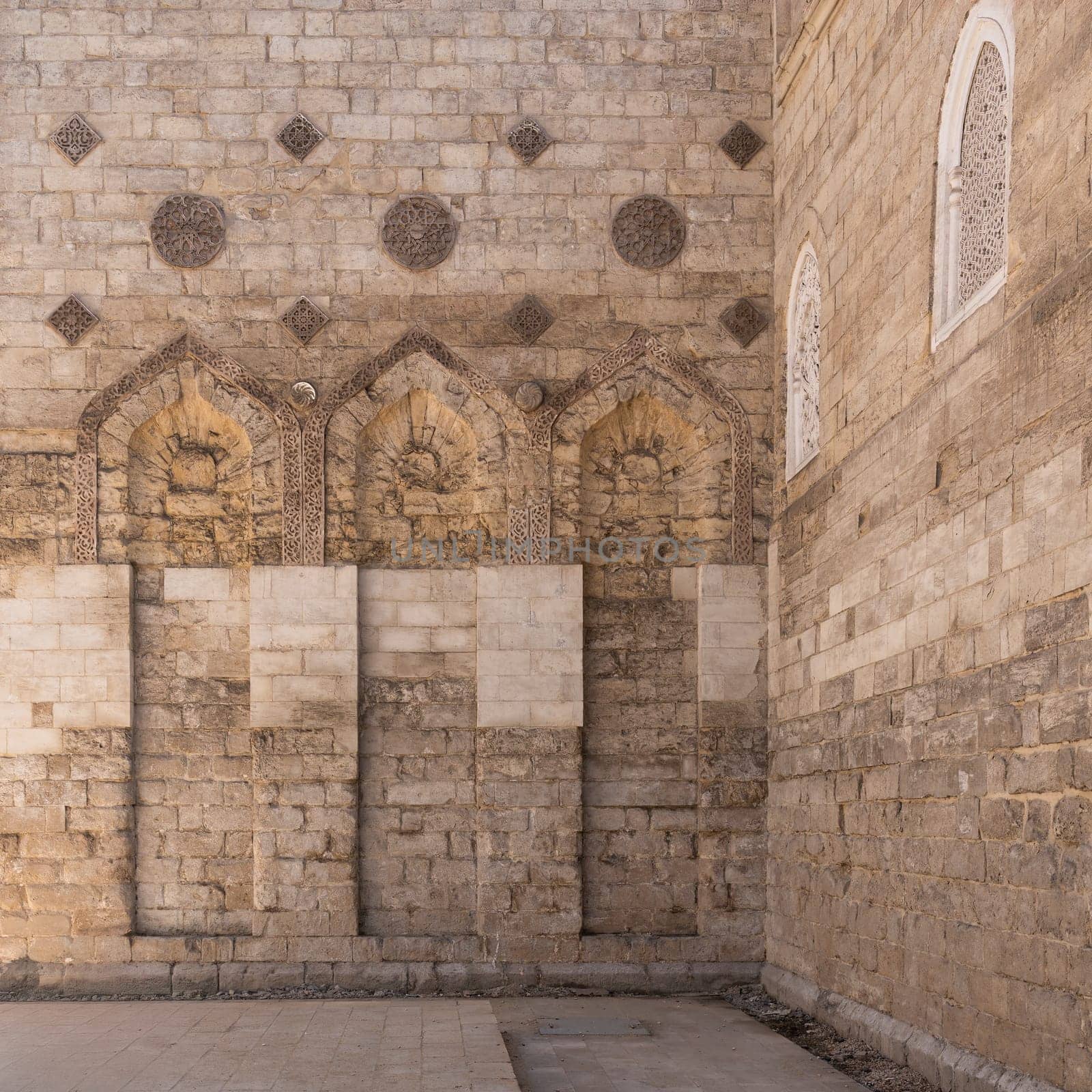 The Mosque of al-Zahir Baybars stands majestic in Cairo, Egypt, showcasing intricate stonework and architectural details under soft golden hour light