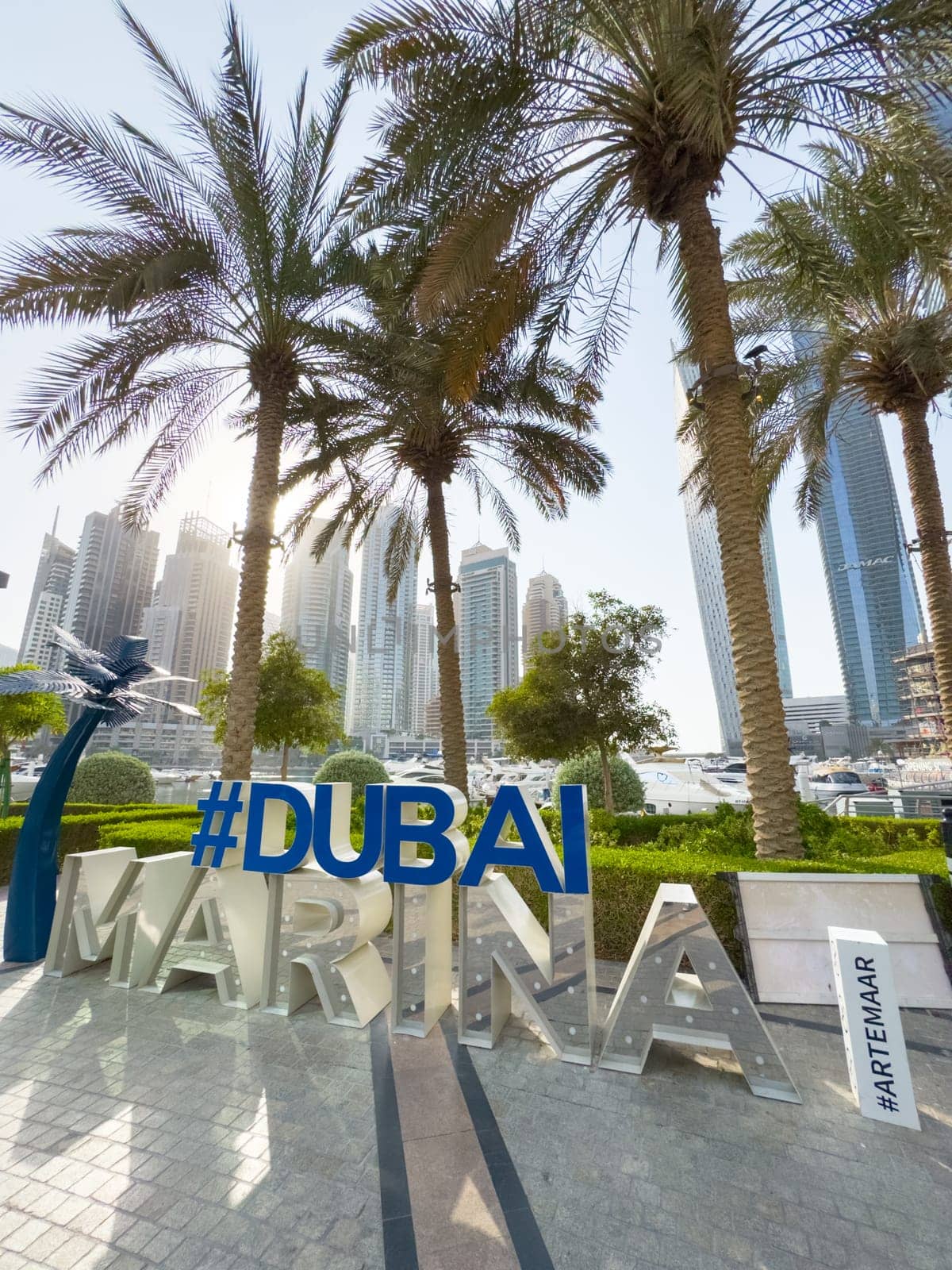 UAE, Dubai, 29 September 2024: Dubai Marina art object against the background of palm trees and skyscrapers on a clear sunny morning. High quality photo