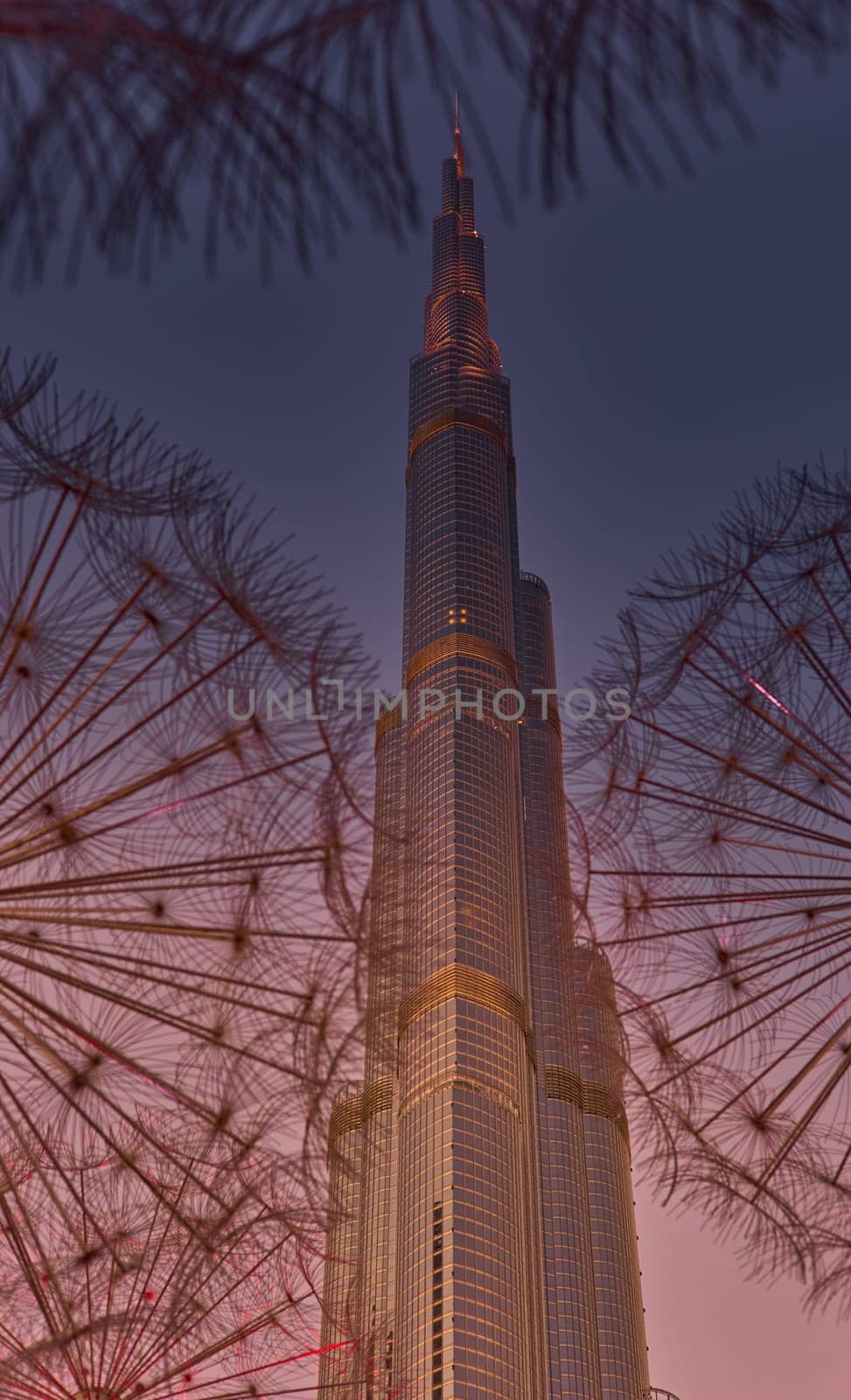UAE, Dubai, 11 December 2024: The famous Burj Khalifa skyscraper through the art object metal dandelions at dusk, Dubai's sights during the incredible sunset sky, skyscrapers illuminated. High quality photo