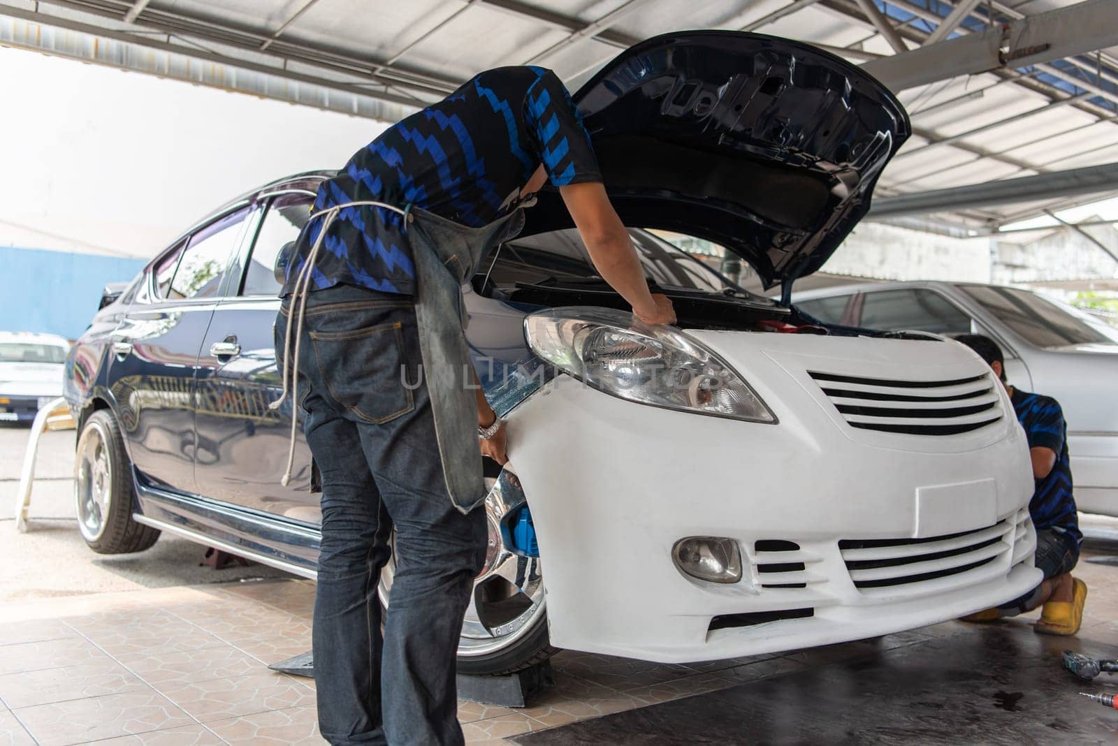 Denter or car mechanic serviceman check and fix body work and fiber bumper body part for fix and repair problem at car garage or repair shop