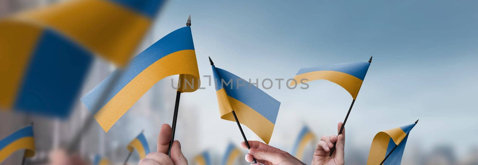 Ukraine flags in their hands on a blurred urban background. The photo illustration was created without the use of artificial intelligence, only using Photoshop.