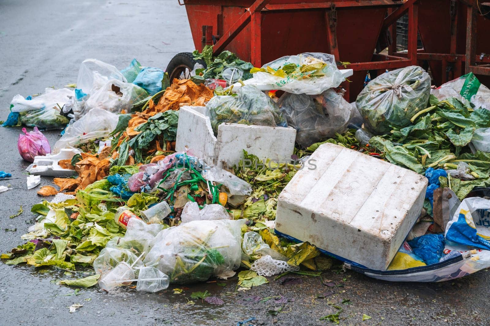 Close-up of a pile of junk and a dumpster next to overflowing dumpsters. Plastic bags, cardboard boxes, and organic waste. Nha Trang, Vietnam - December 13, 2024