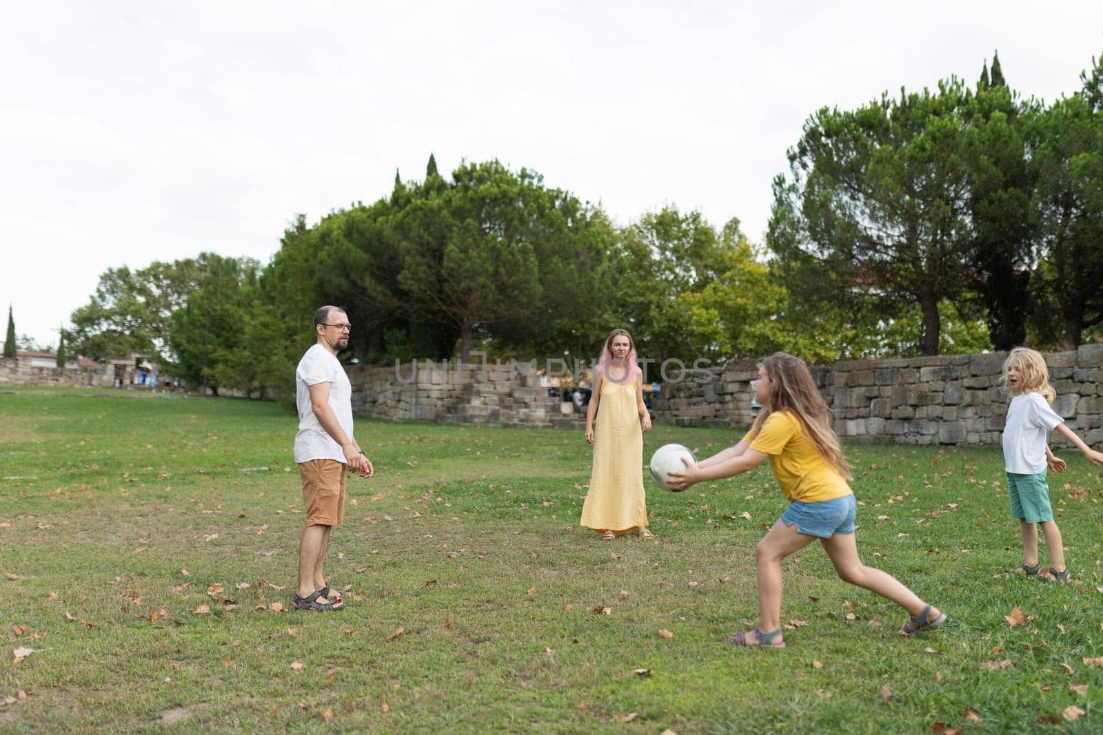 Family enjoying leisure time, playing volleyball together in park, promoting healthy lifestyle and family bonding