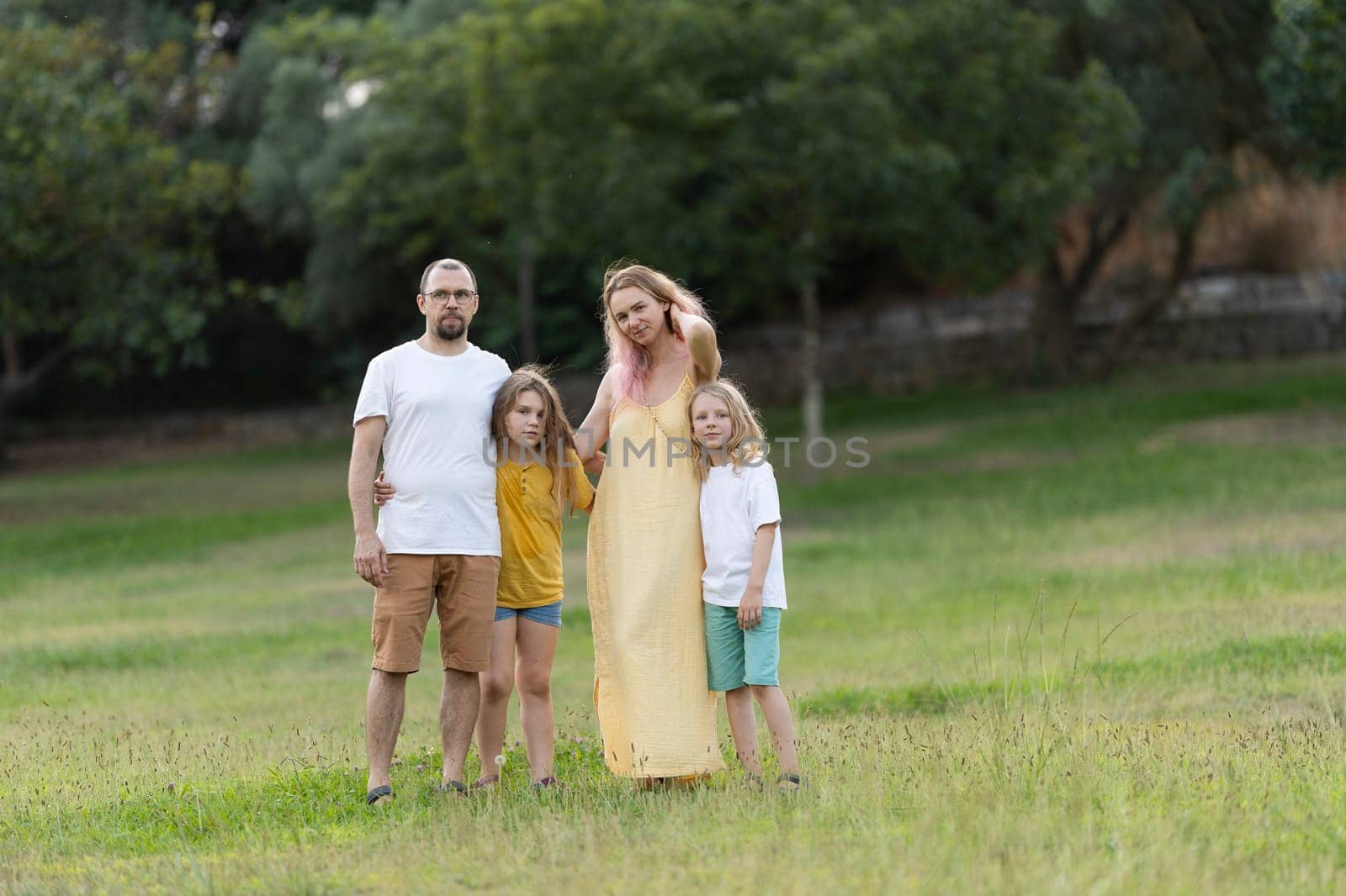 Family posing together in green meadow on summer day