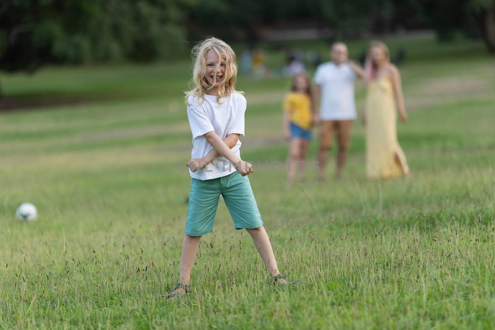 Child having fun with his family in a green park during a summer afternoon