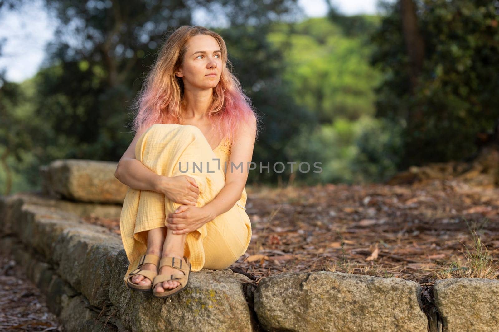 Young woman with pink hair enjoying a peaceful moment in nature, finding solace and introspection amidst the tranquil surroundings