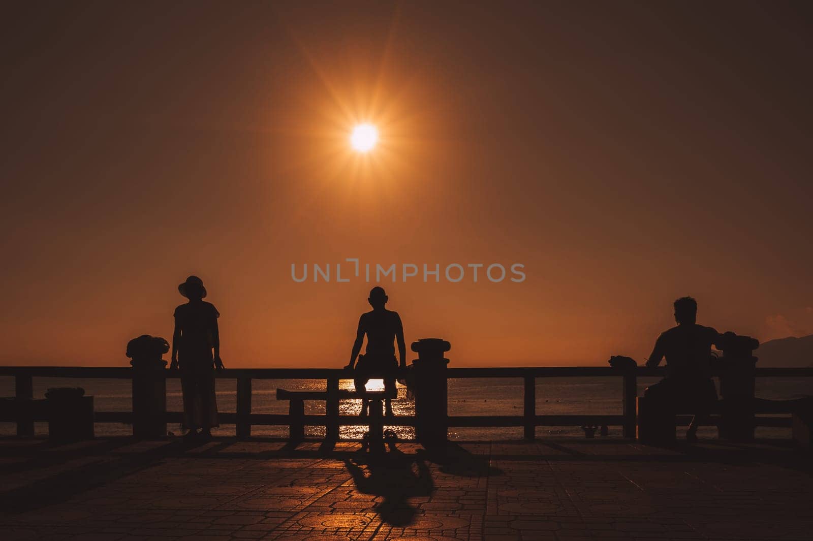 silhouette of people relaxing by the sea on embankment in the morning at the resort