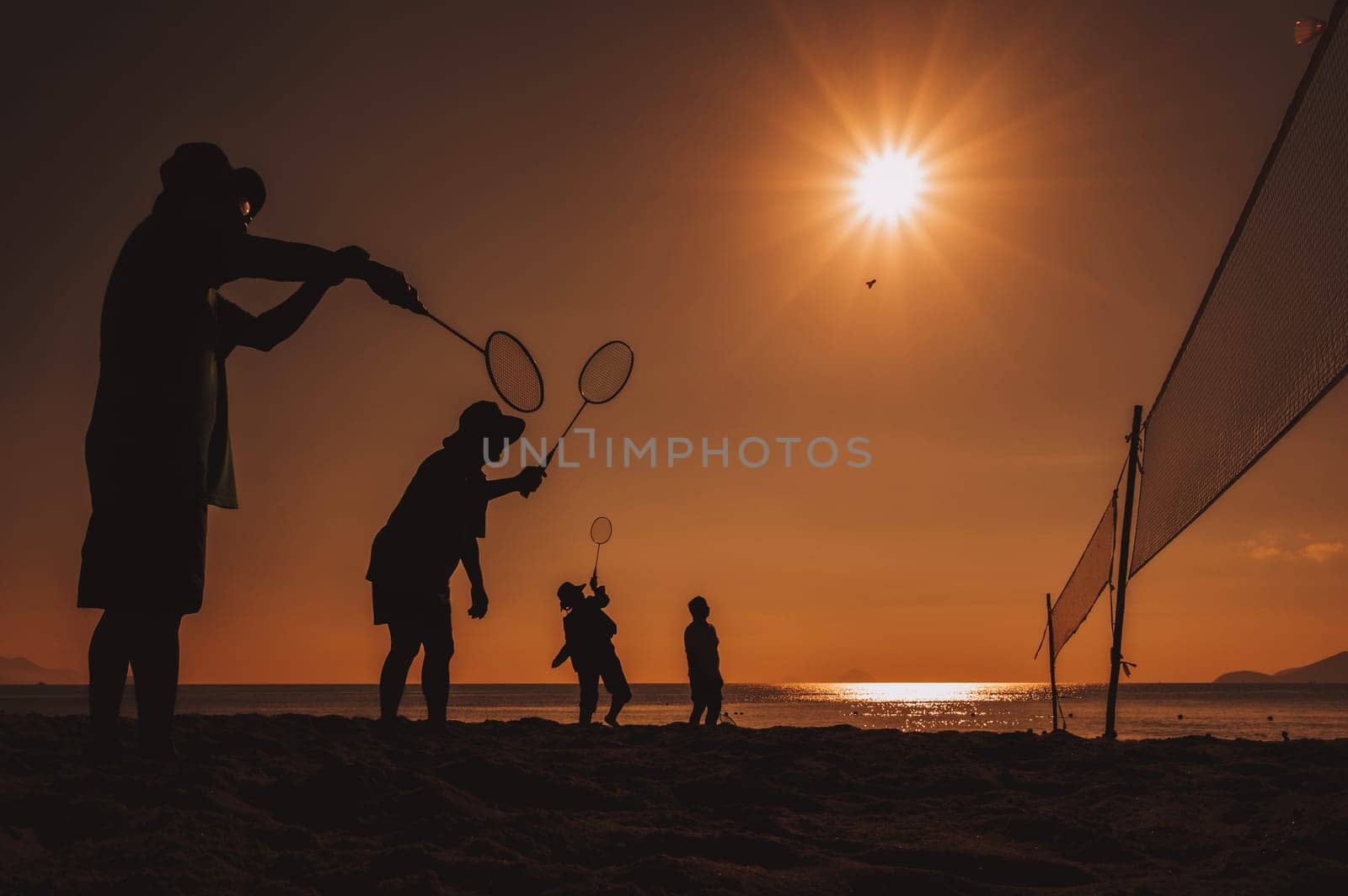 silhouettes of elderly Asian people playing badminton on the beach by the sea in the morning at sunrise