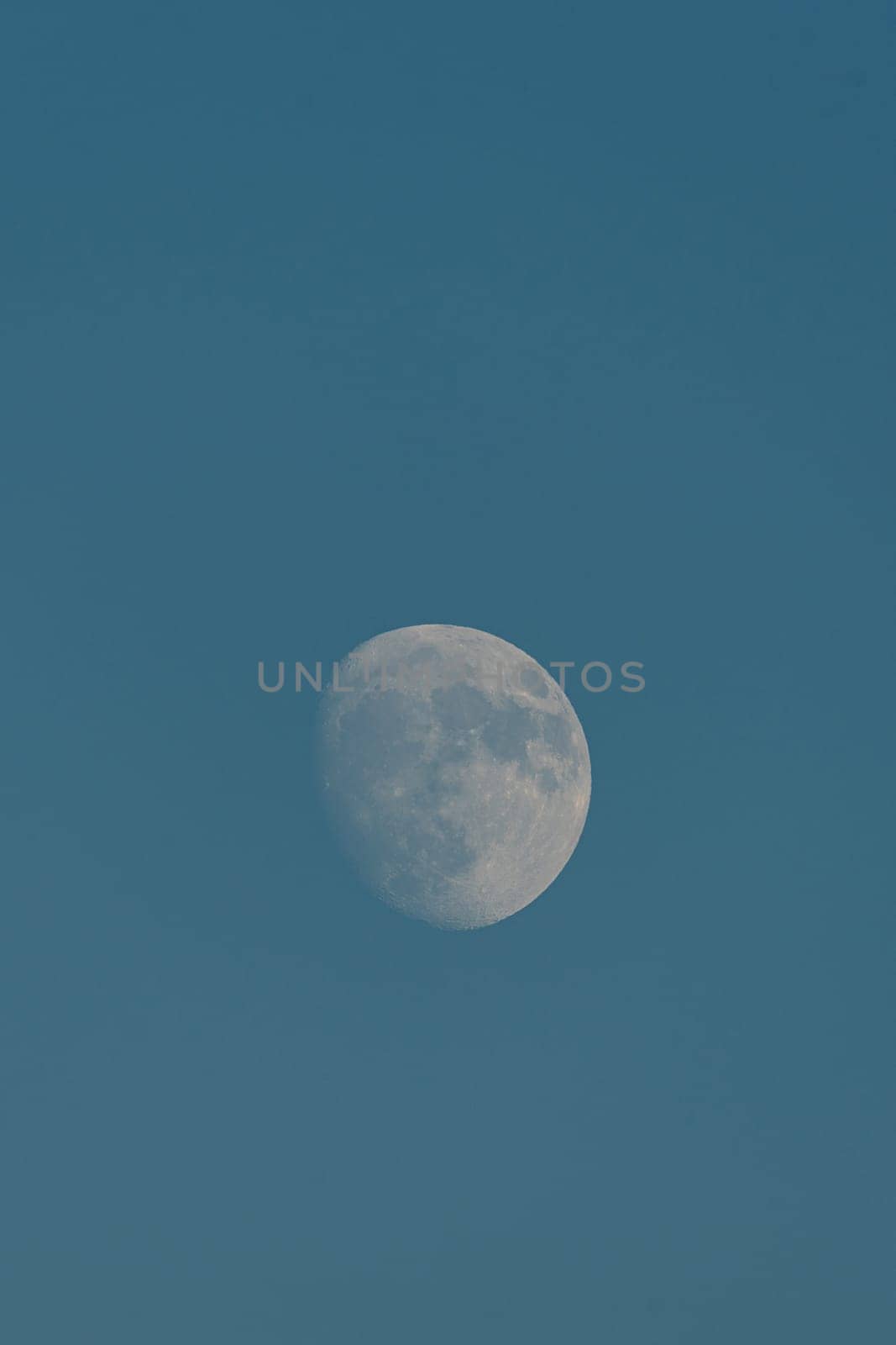 Almost full moon over a blue sky.Details of the craters, solitary, empty space, sky with light.