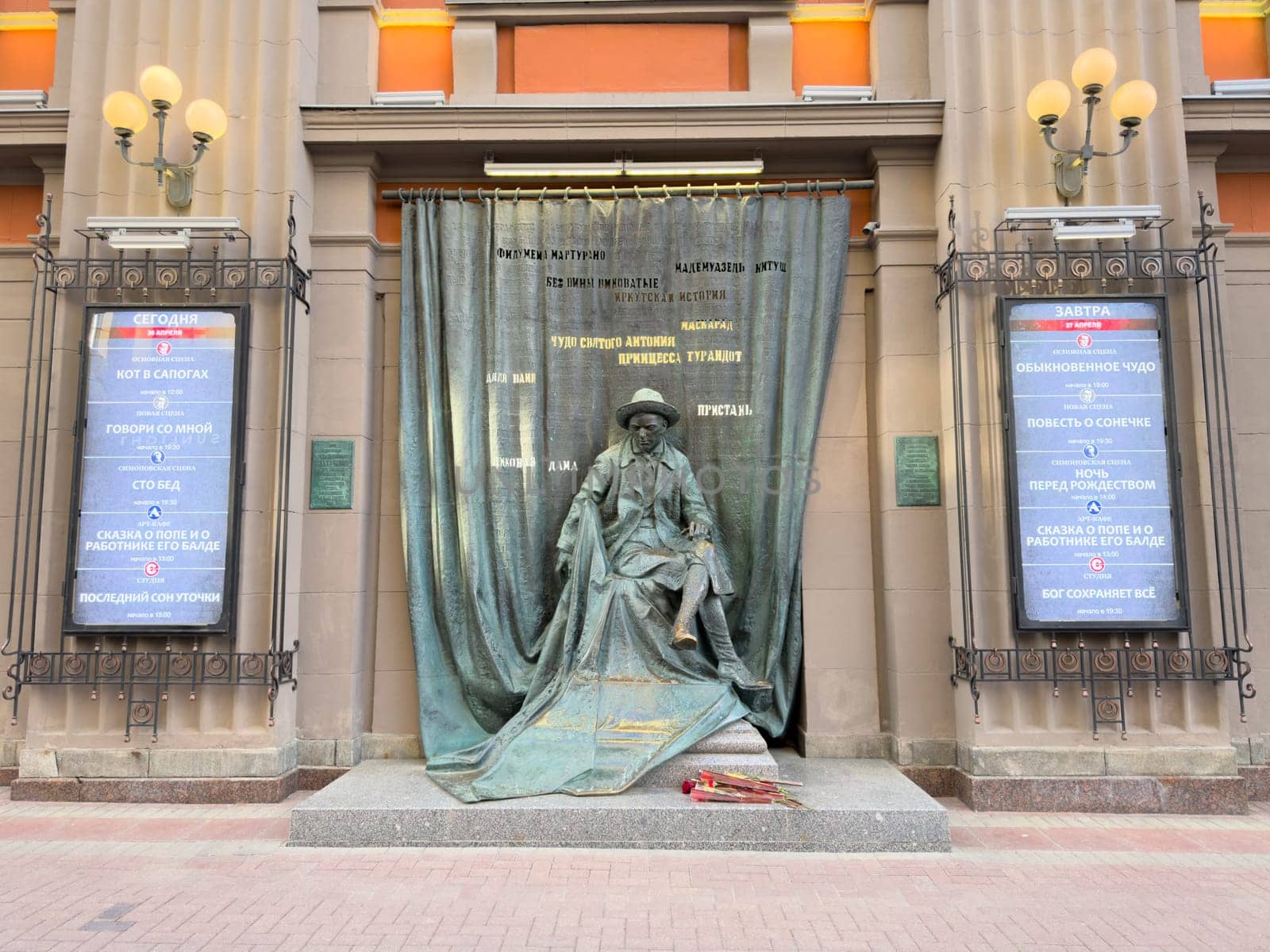 Moscow, Russia, April 26, 2025: Monument near the Vakhtangov State Academic Theater honoring Russian theatrical legacy, with bronze statue and posters for current and upcoming stage performances